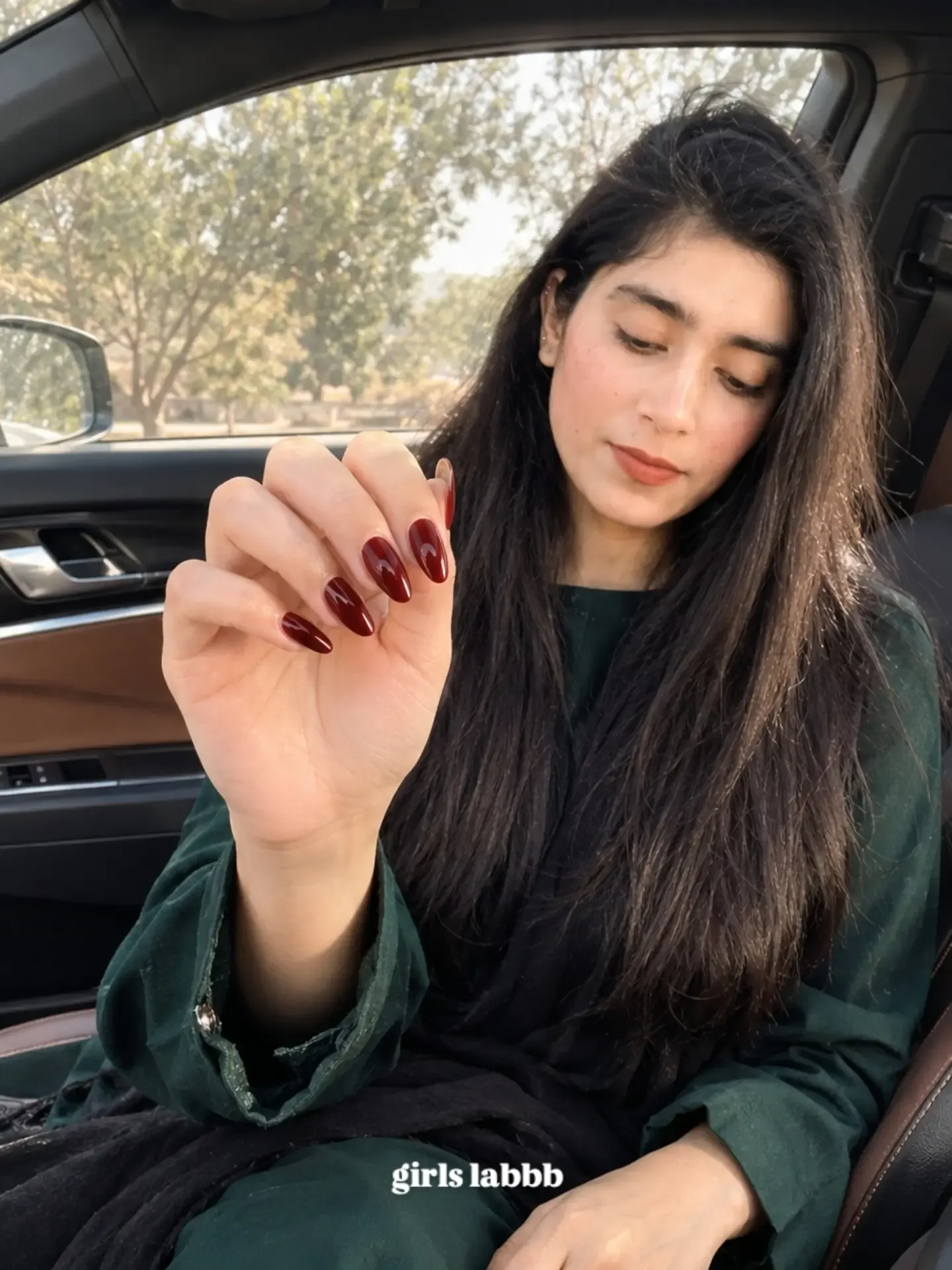 Glossy wine colored almond nails shown in daylight