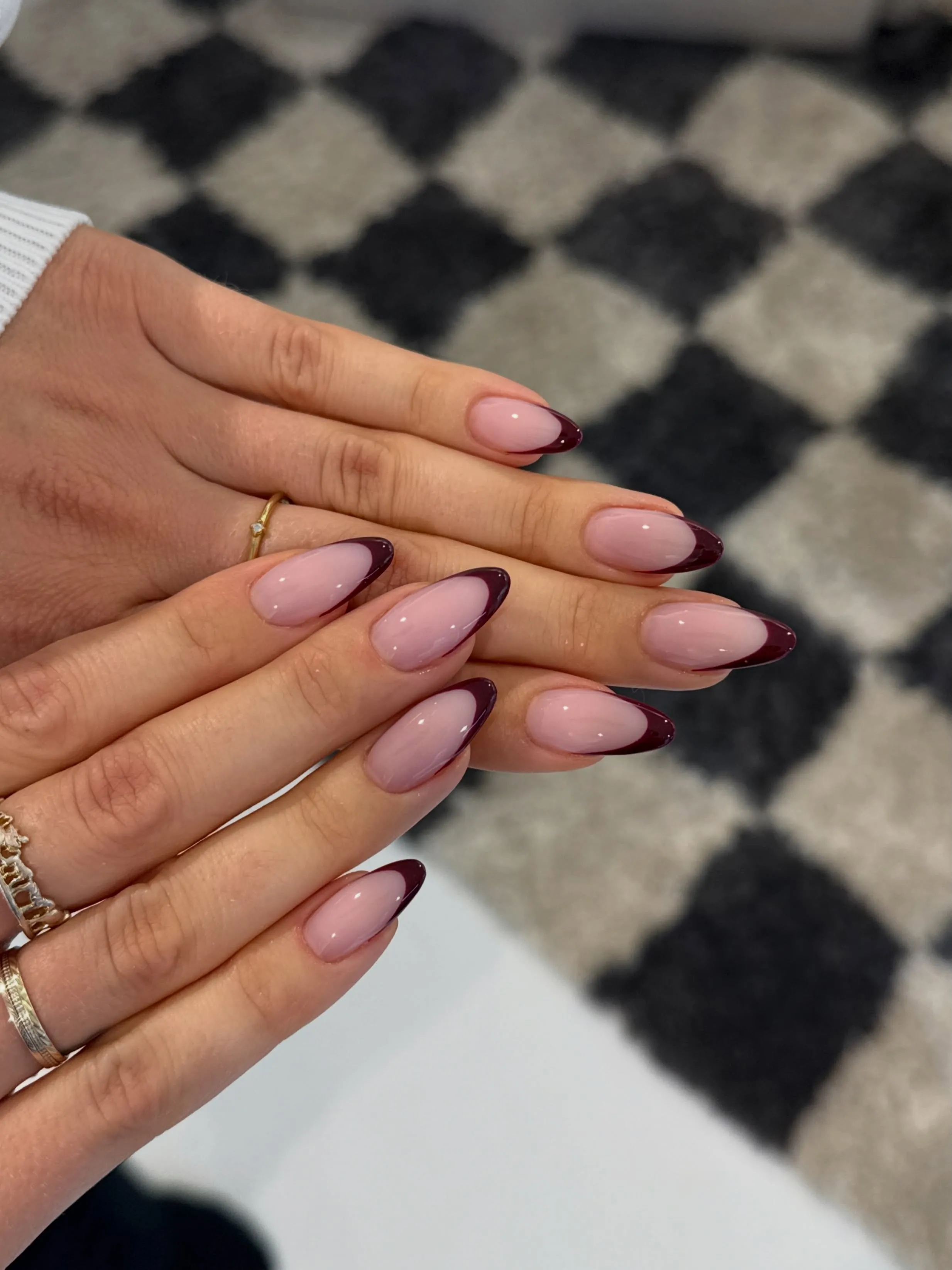 Pale pink almond nails framed with thin burgundy edges