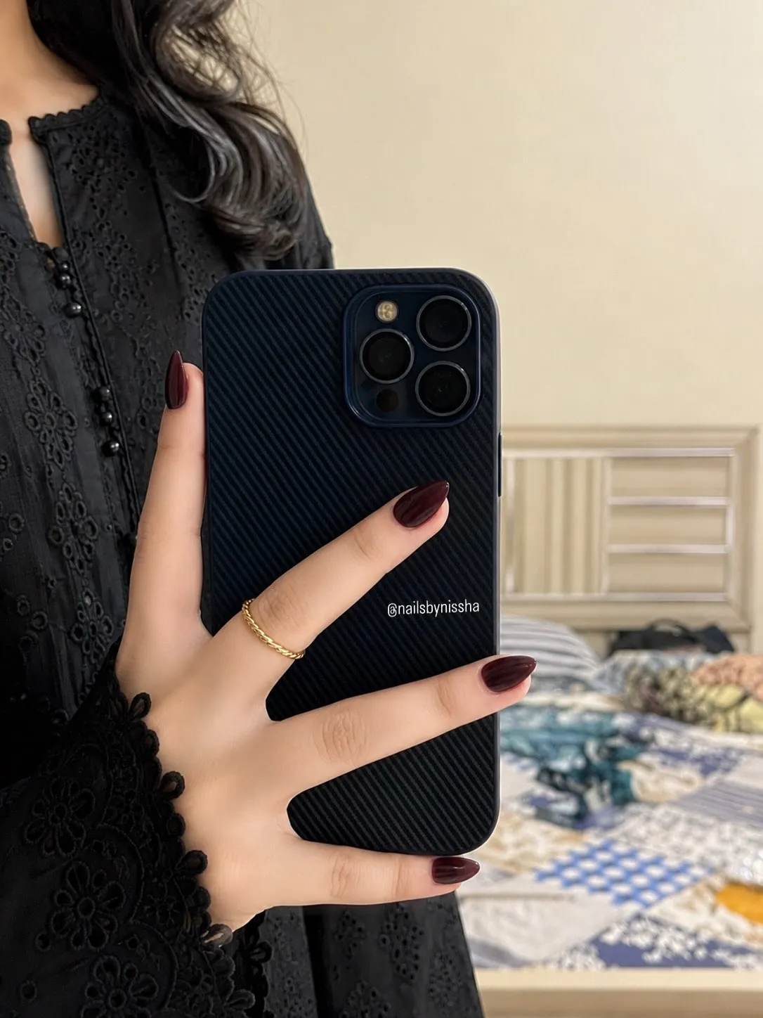 Short burgundy almond nails shown holding a phone
