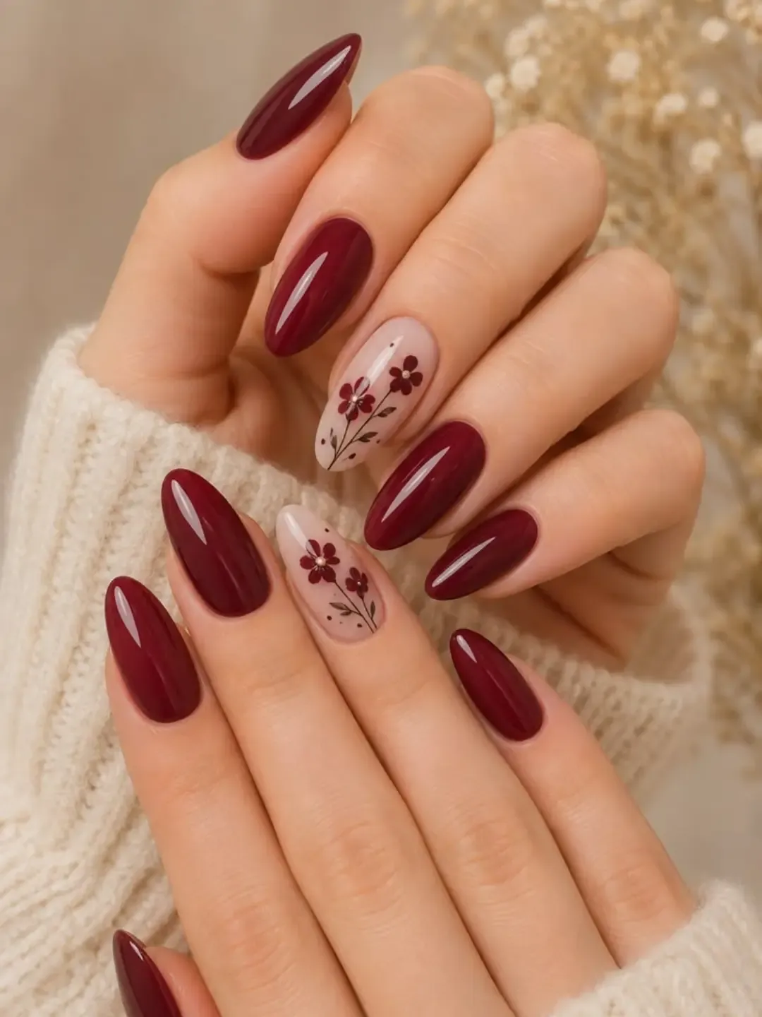 Solid burgundy almond nails paired with pale botanical accents
