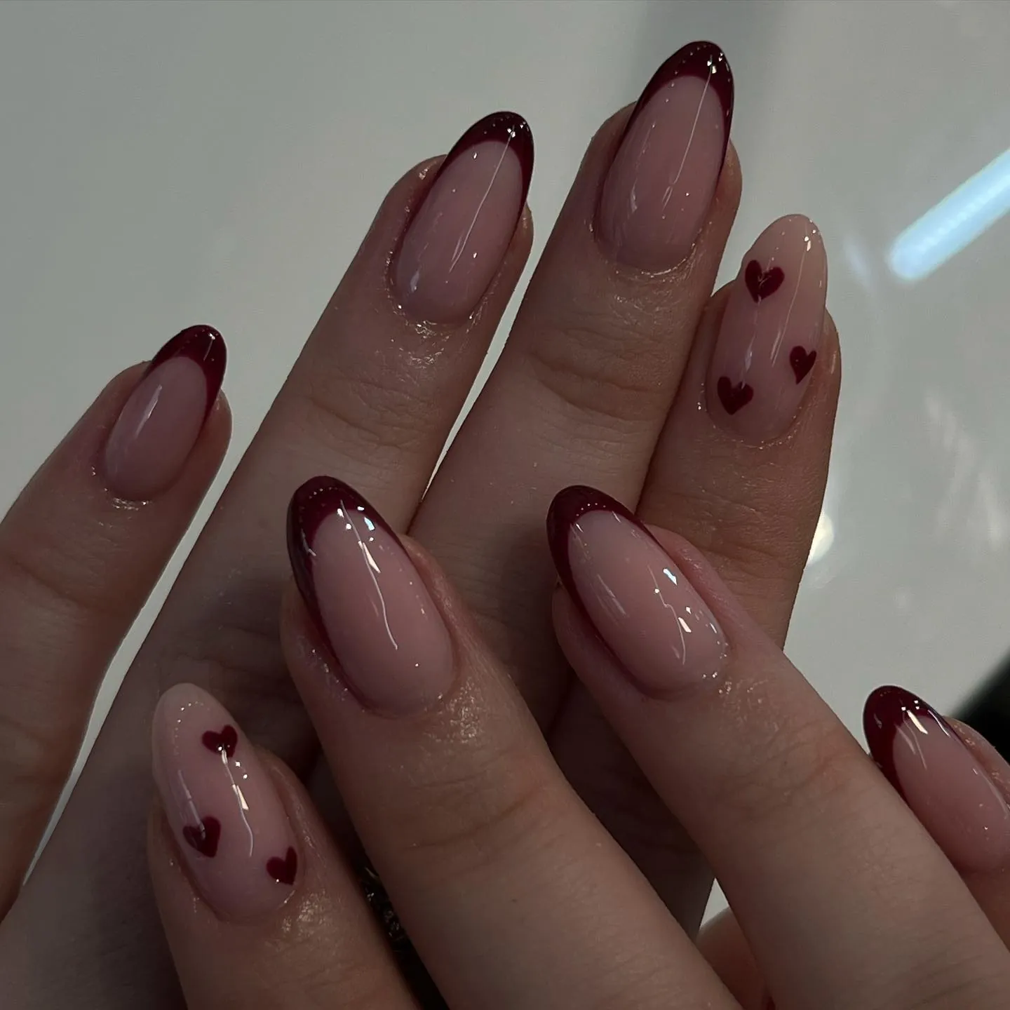 Burgundy almond French tips with small hearts on pink accent nails
