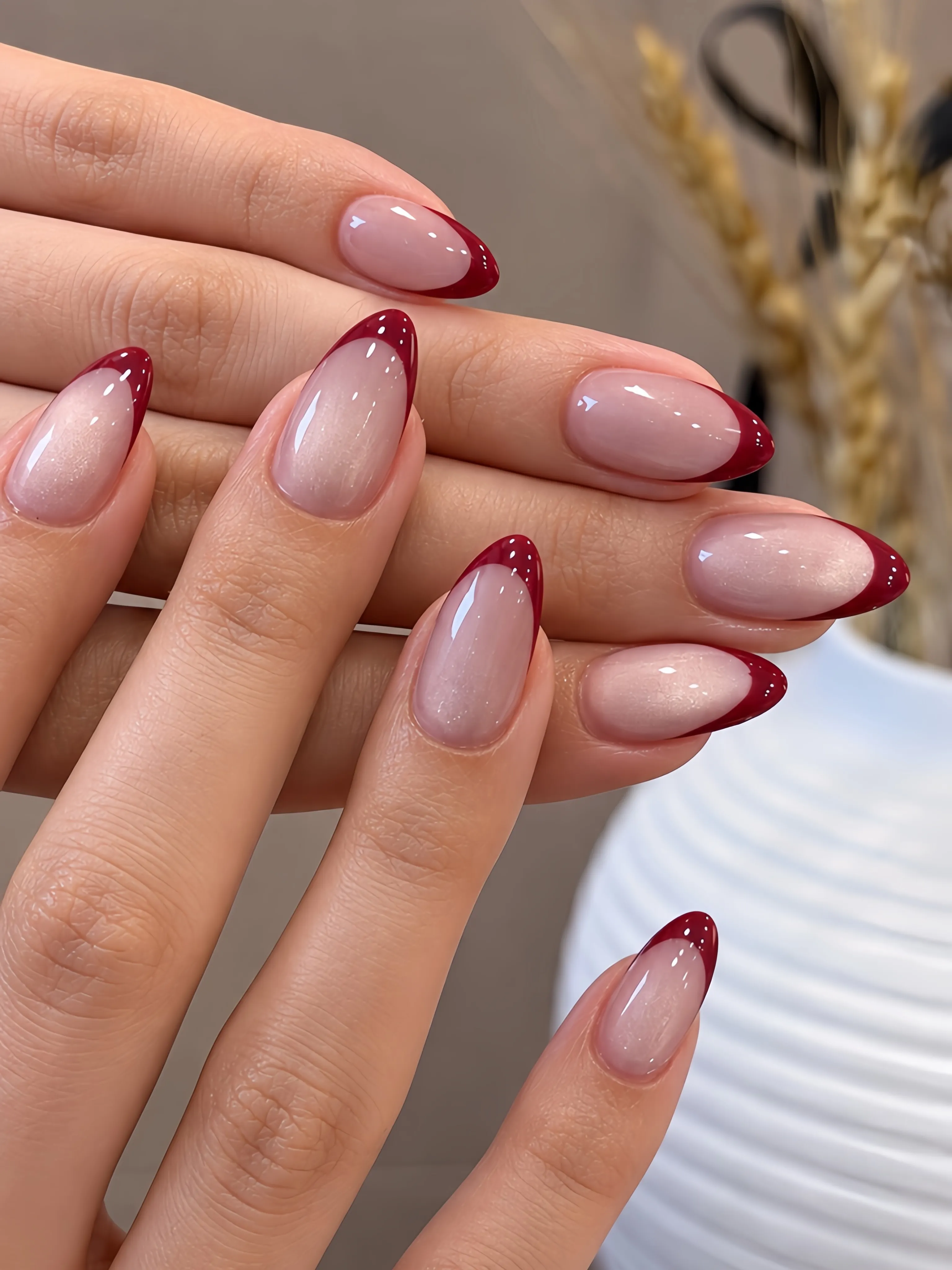 Glossy pink almond nails with red burgundy tips and pale speckles