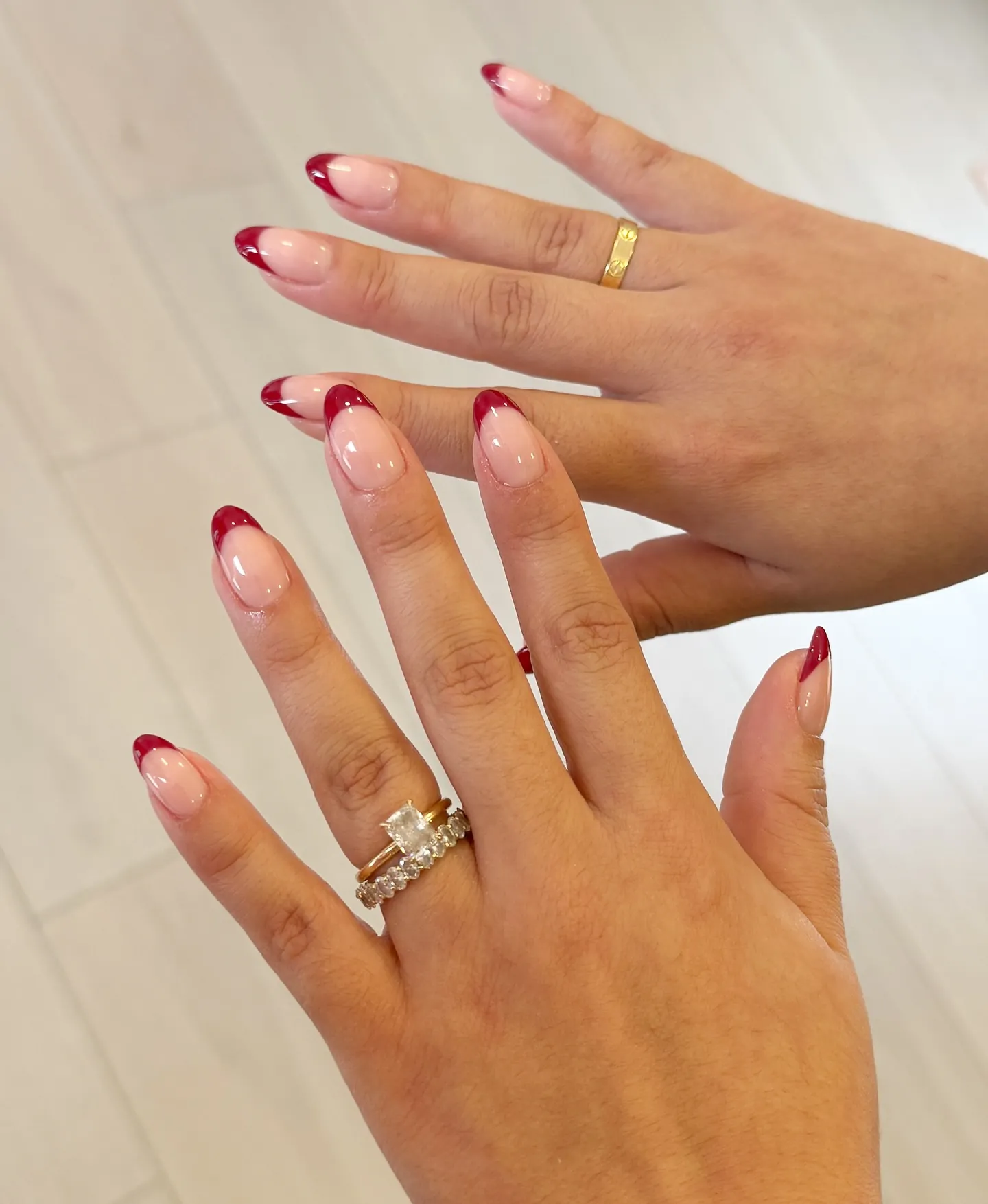 Long almond nails with sheer pink bases and red burgundy French tips