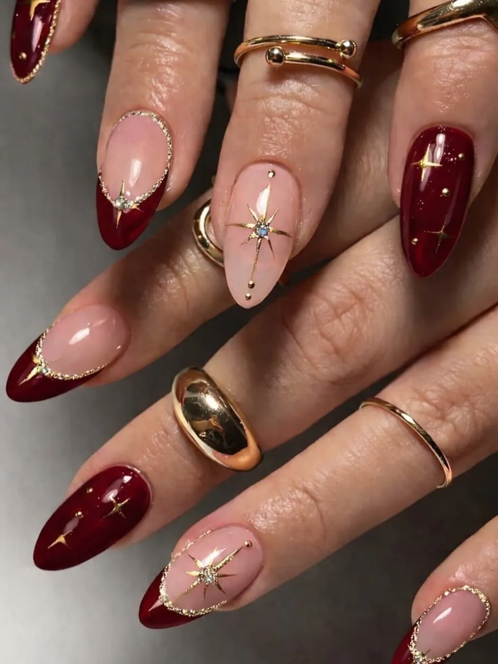 Burgundy French and solid nails with gold starbursts on pink accents