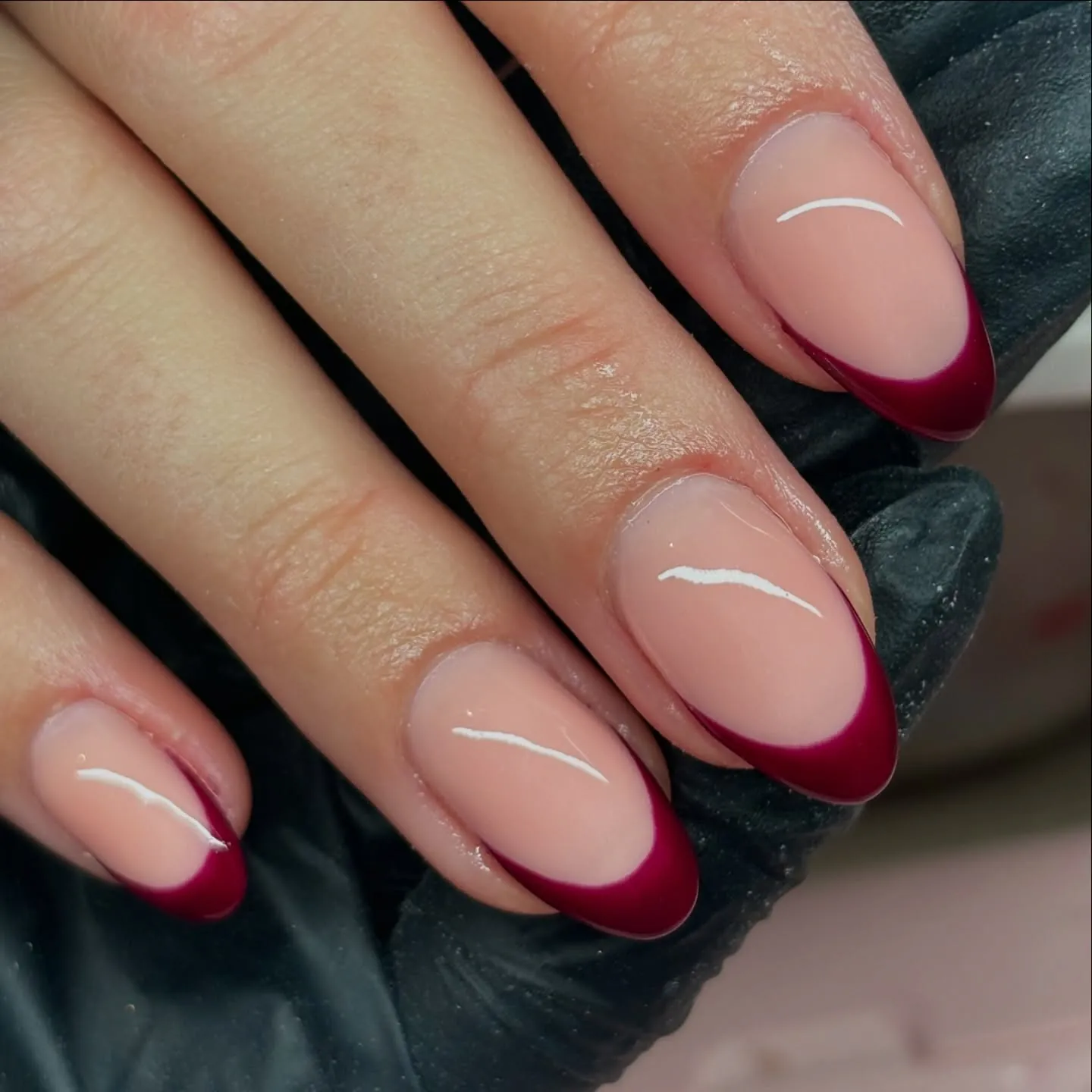 Rounded pink nails with broad glossy burgundy French tips