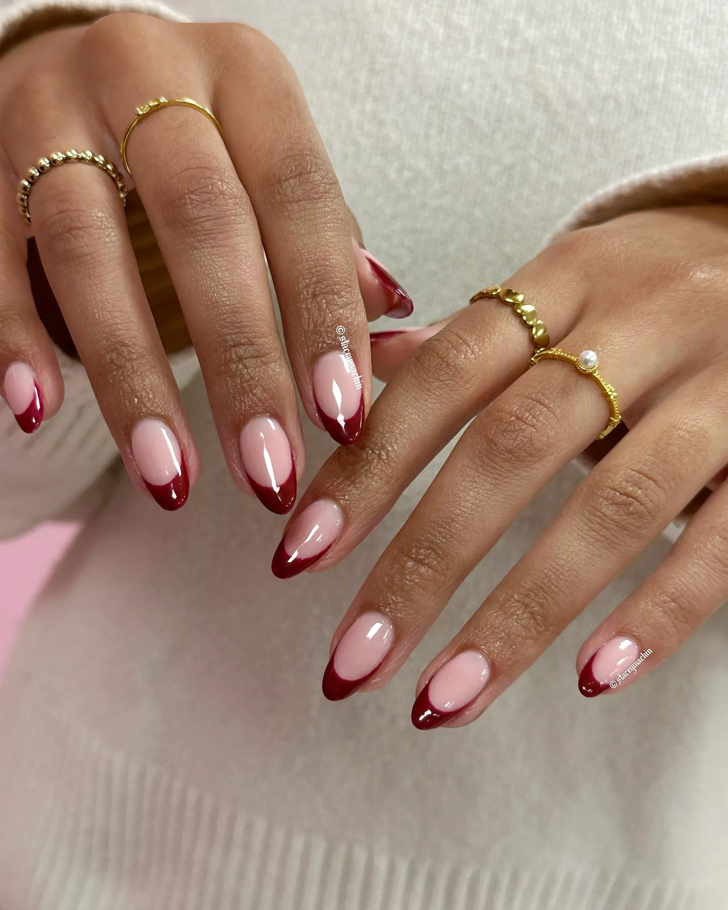 Pale pink almond nails with curved burgundy red tips