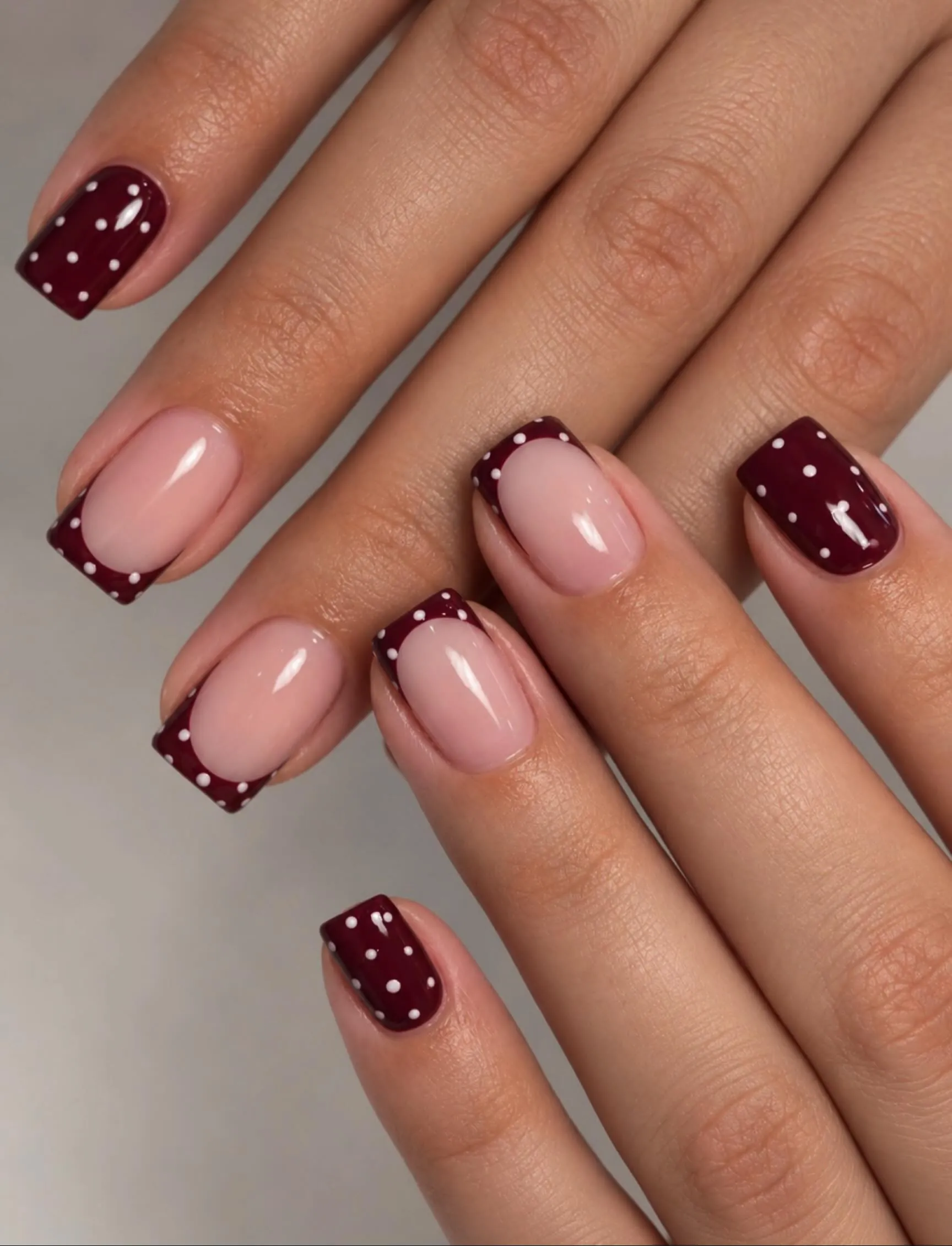 Short square nails mixing dotted burgundy color and pink French accents