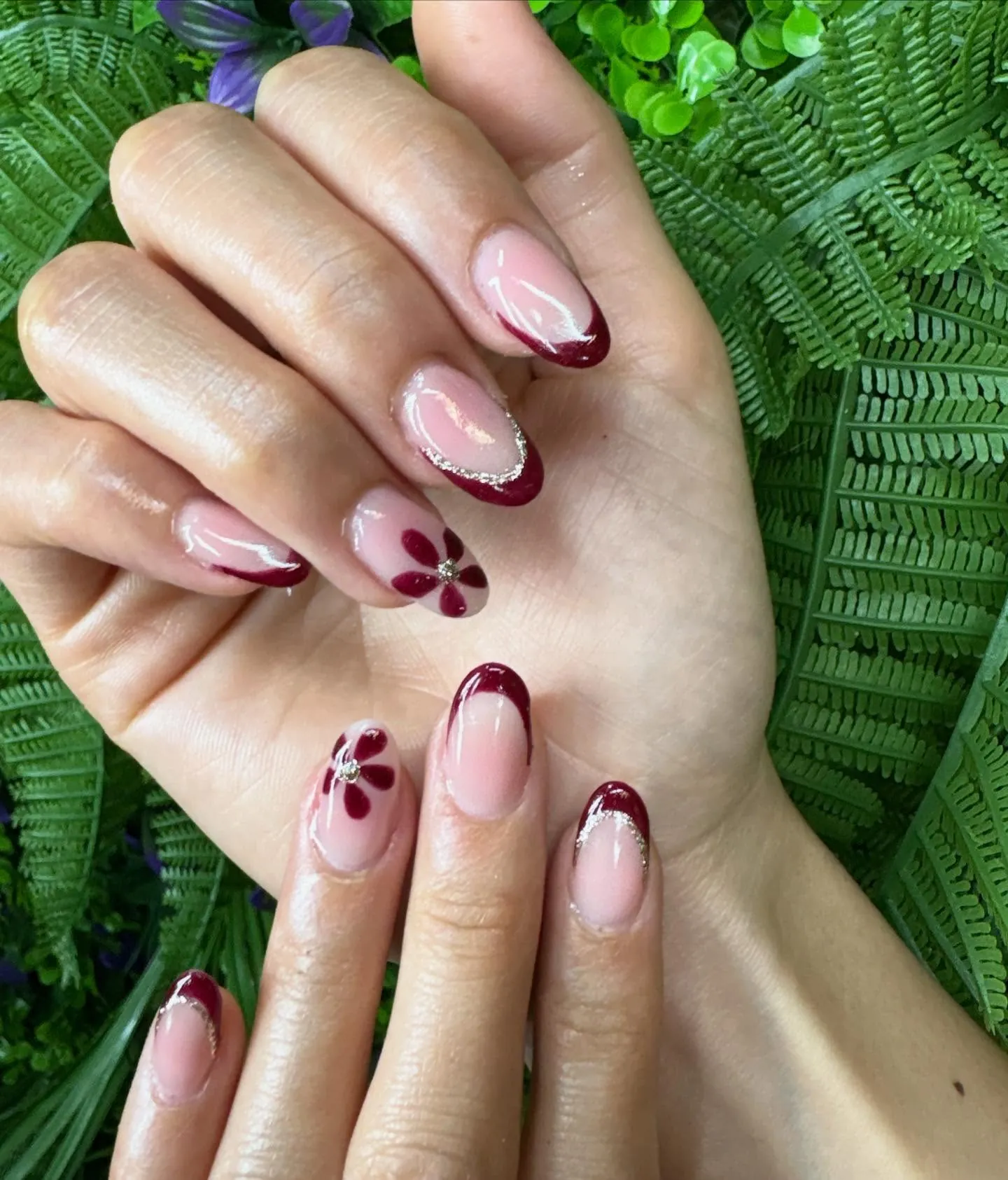 Pink almond nails with burgundy French tips and burgundy flower petals