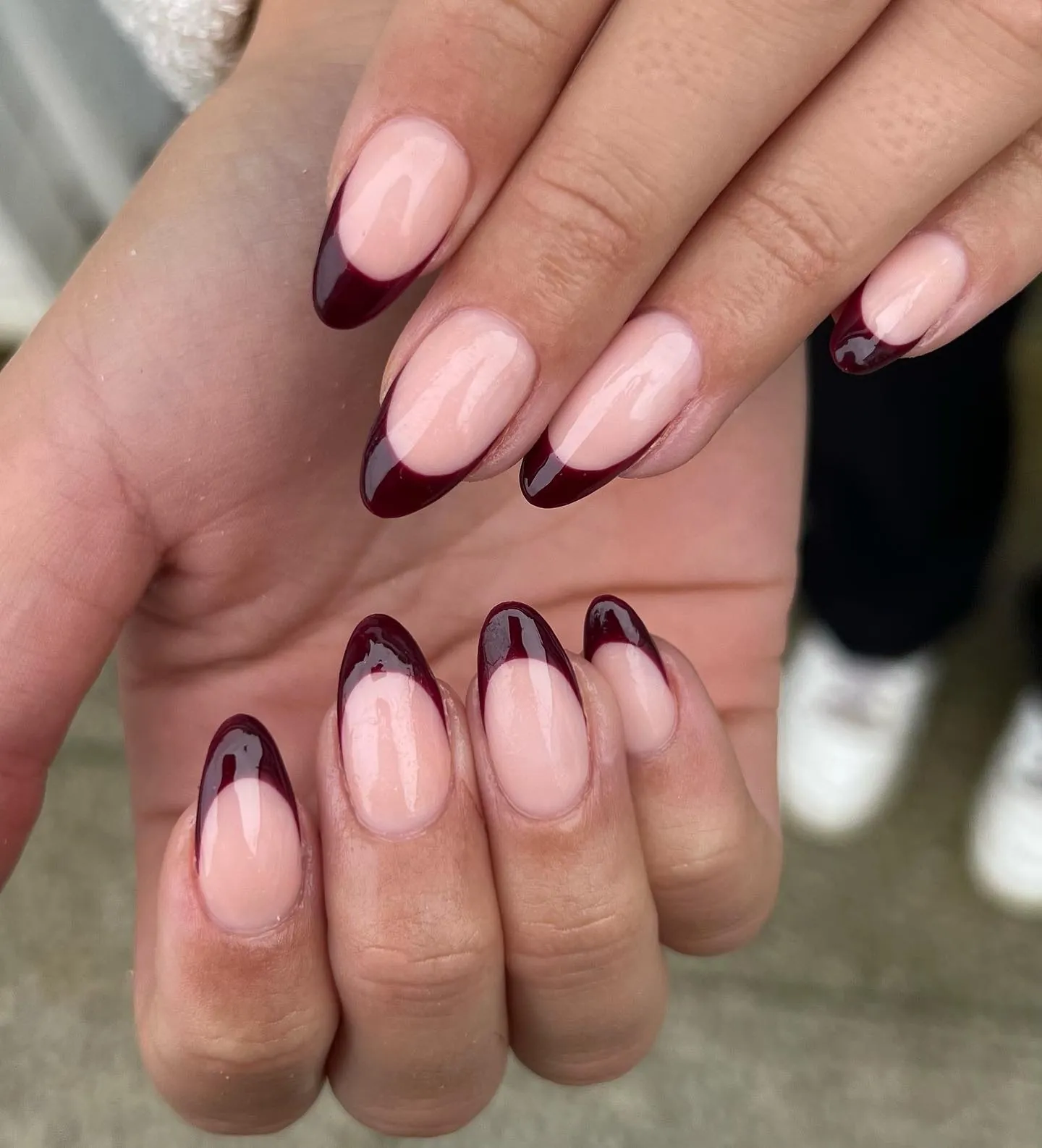 Pink almond nails with dark burgundy tips and fine curved inner lines