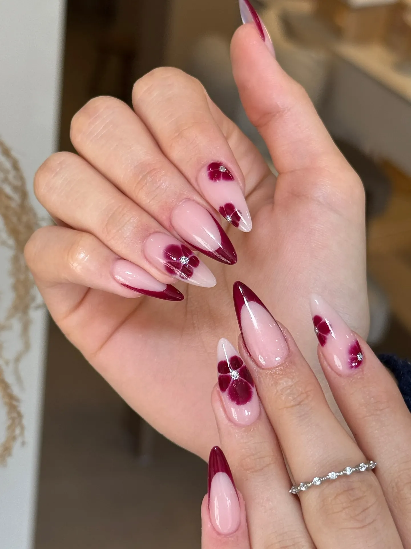 Long almond nails with burgundy tips and burgundy floral accents