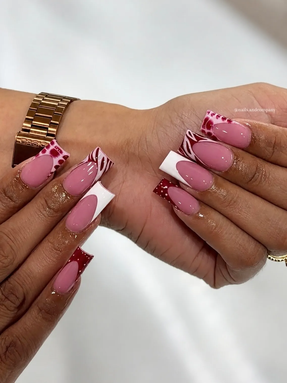Pink square nails with white tips, burgundy spots and striped accents