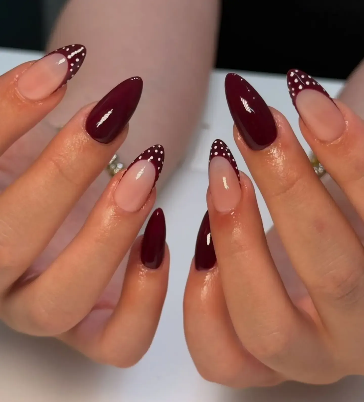 Long almond nails with solid burgundy and white-dotted burgundy French tips