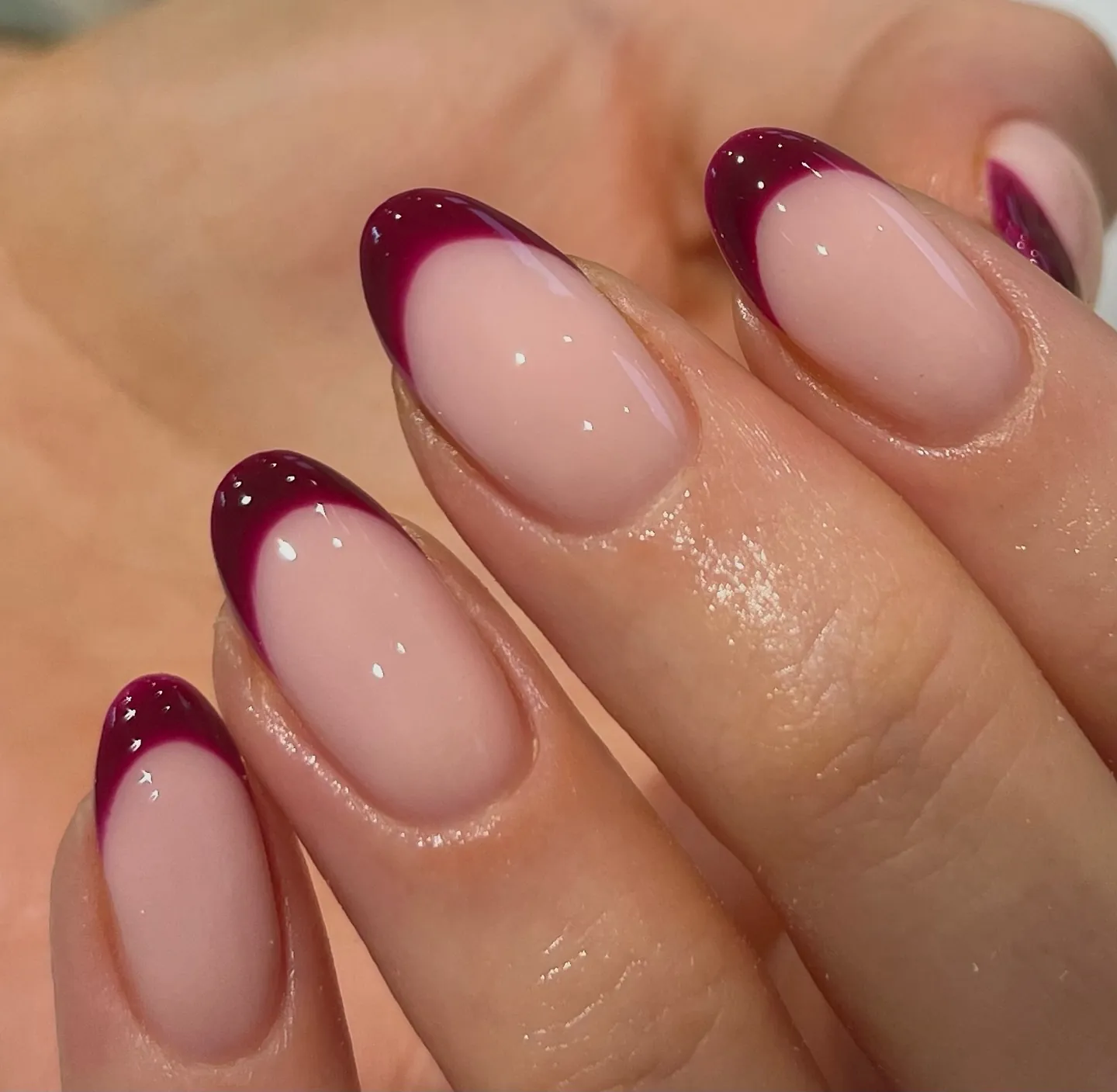 Pink almond nails with burgundy French tips and tiny pale specks