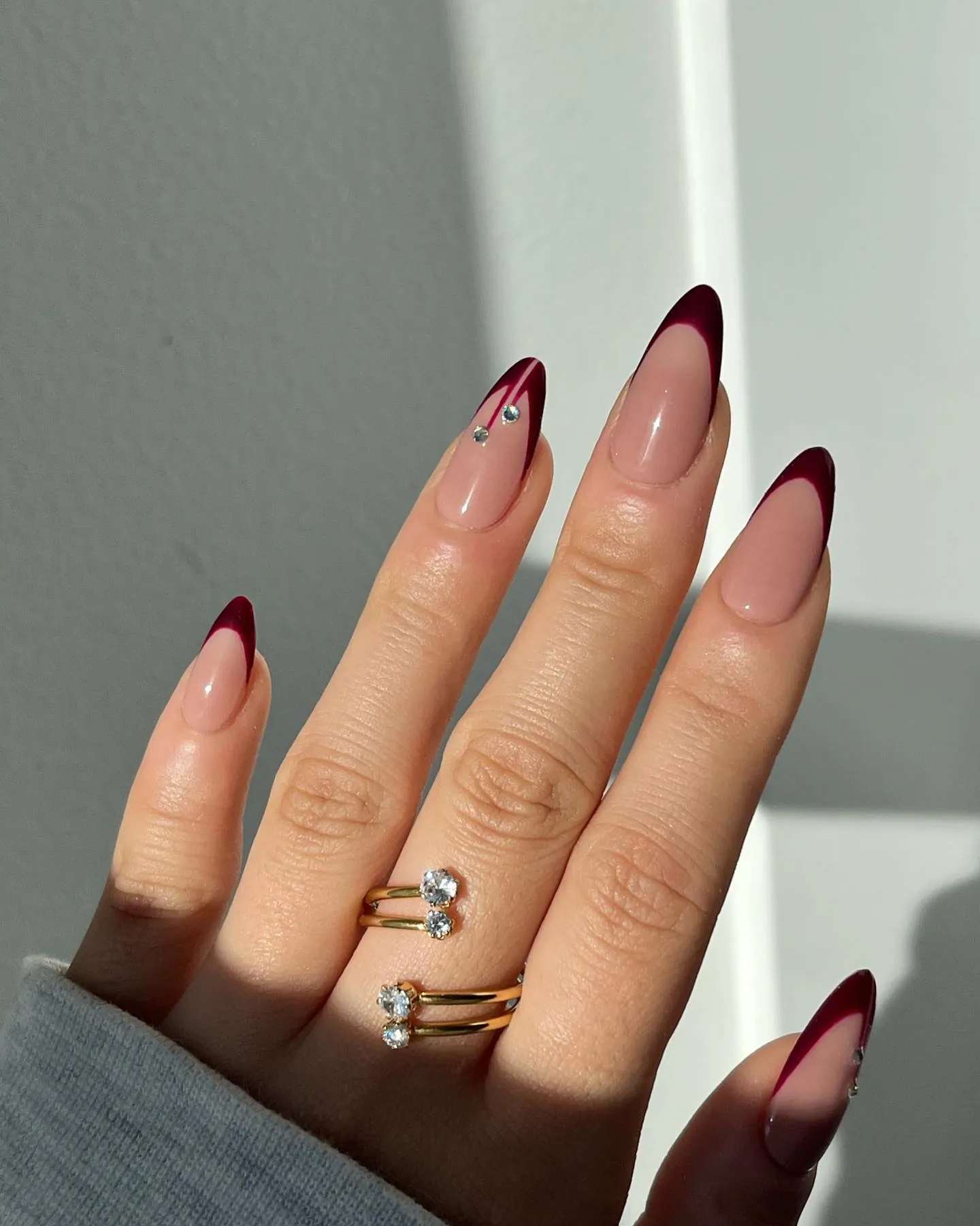 Long almond burgundy French nails with a small cherry accent