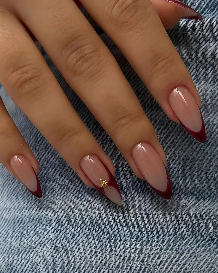 Nude pink pointed nails with fine burgundy tips and a gold detail