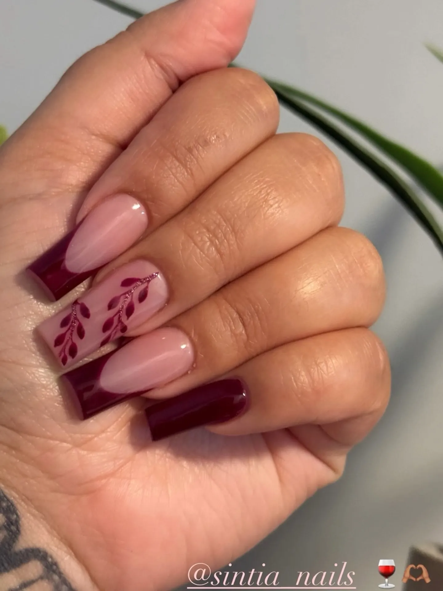 Burgundy square French tips with a nude leaf patterned accent nail