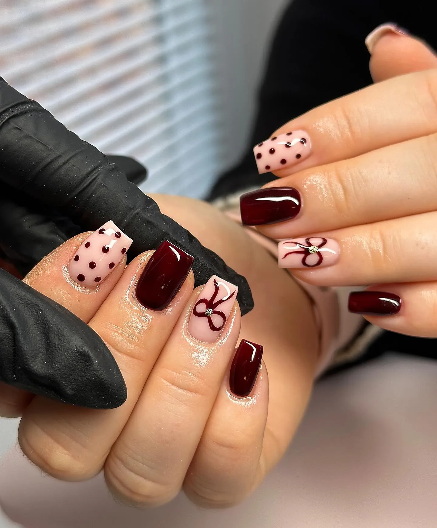 Short burgundy square nails with pink bow and dotted accents