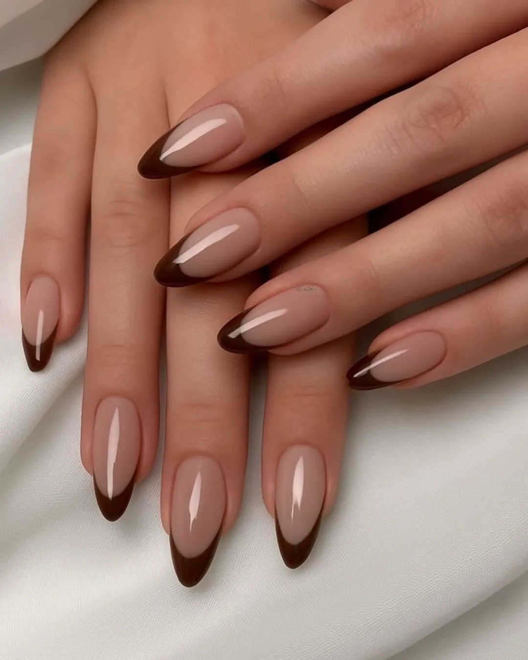 Nude almond nails with glossy deep brown curved tips