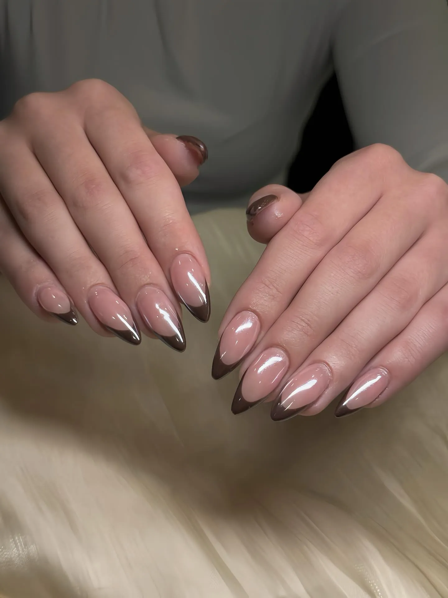 Pearly pink almond nails with reflective dark brown tips