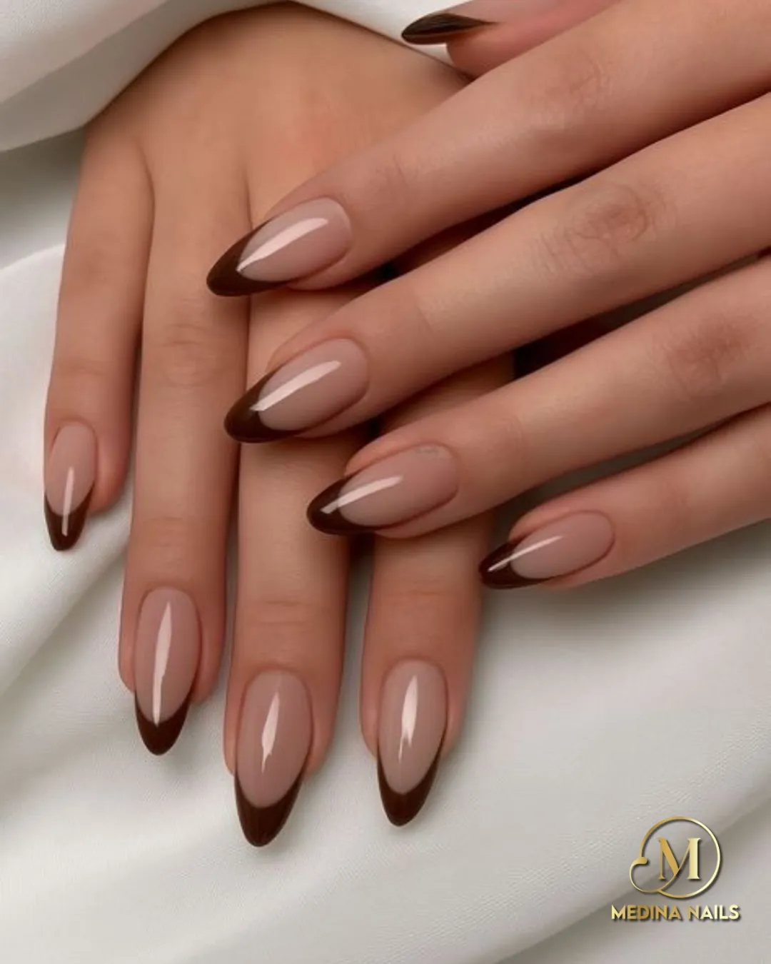 Glossy nude almond nails with curved dark brown French tips