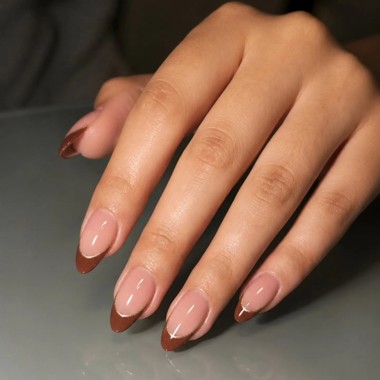 Pink almond nails with fine warm brown French edges