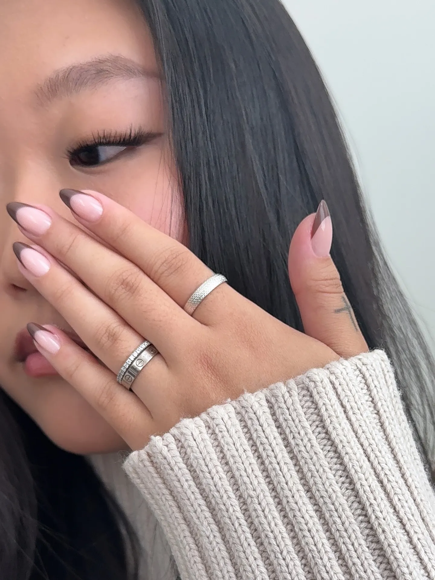 Pink almond nails with asymmetric dark brown French tips