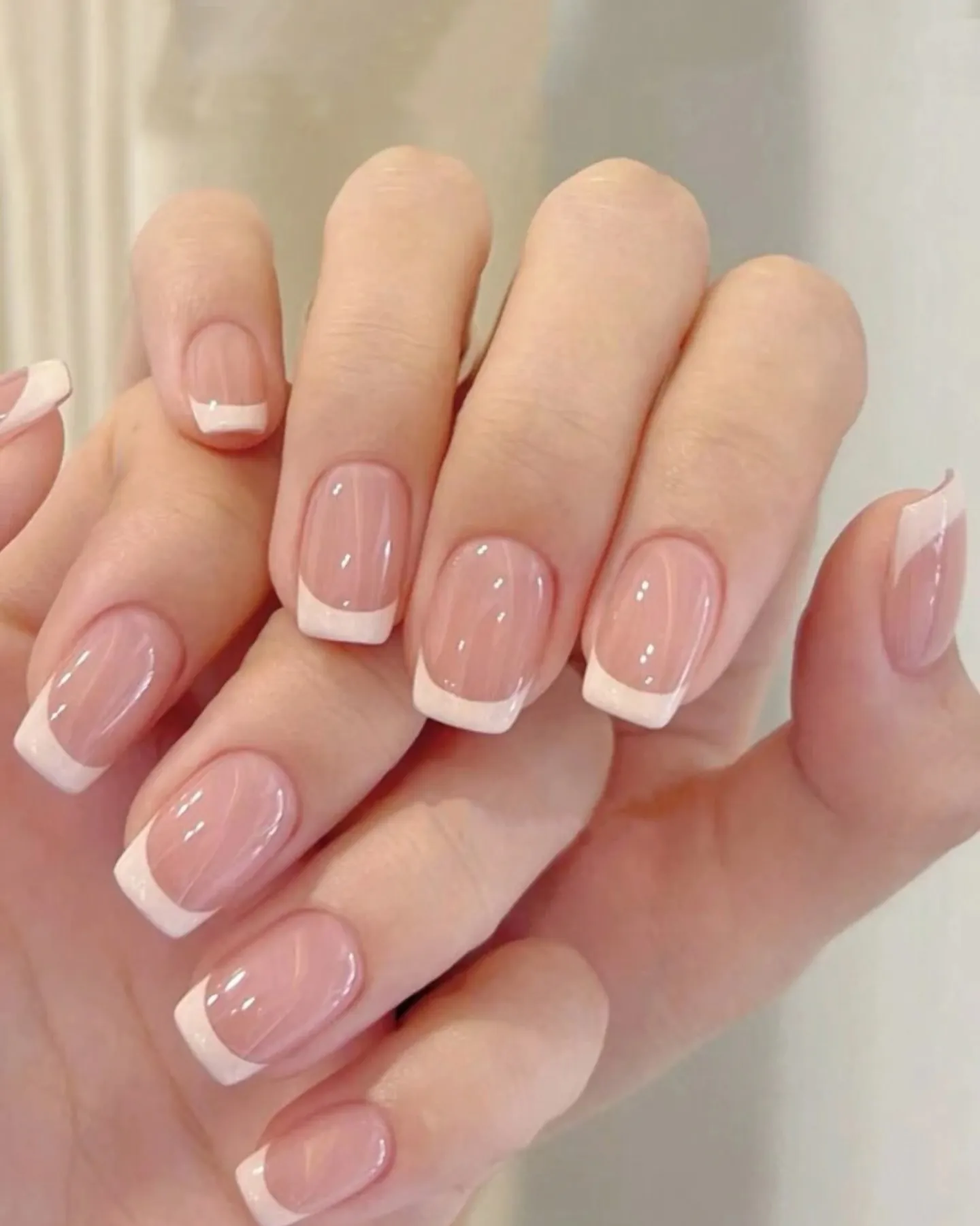 Soft pink square French nails shown in a close view