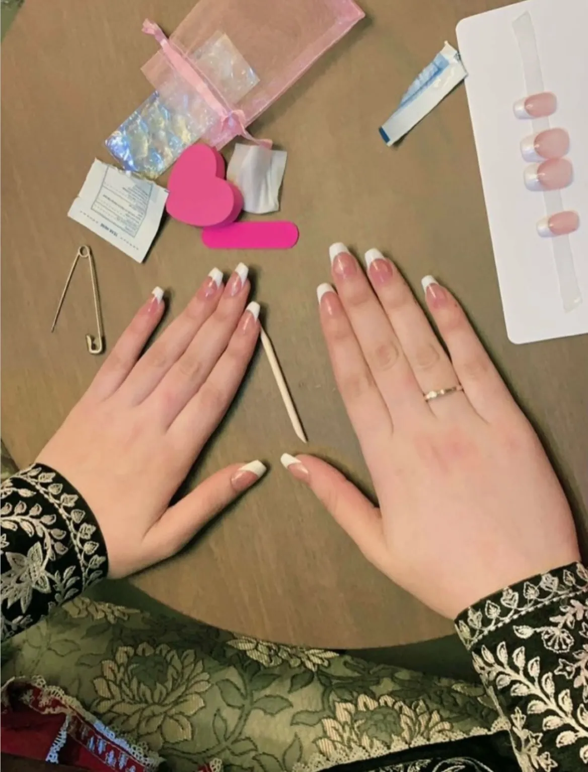 Pink square nails with broad white French tips beside a nail display