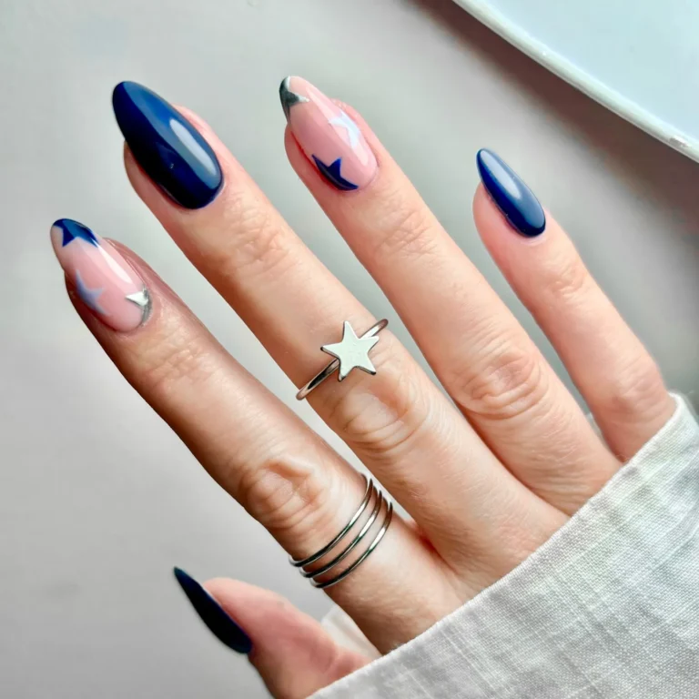 Dark blue star nail art featuring glossy navy blue French tips, delicate white star accents, and elegant almond-shaped nails.
