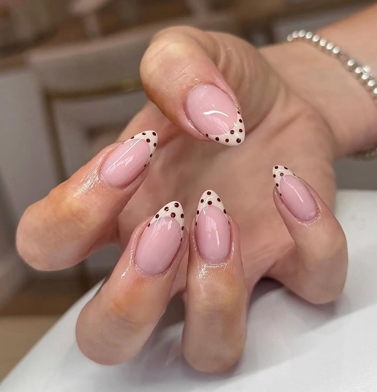 Pink almond nails with pale French tips and dark dots