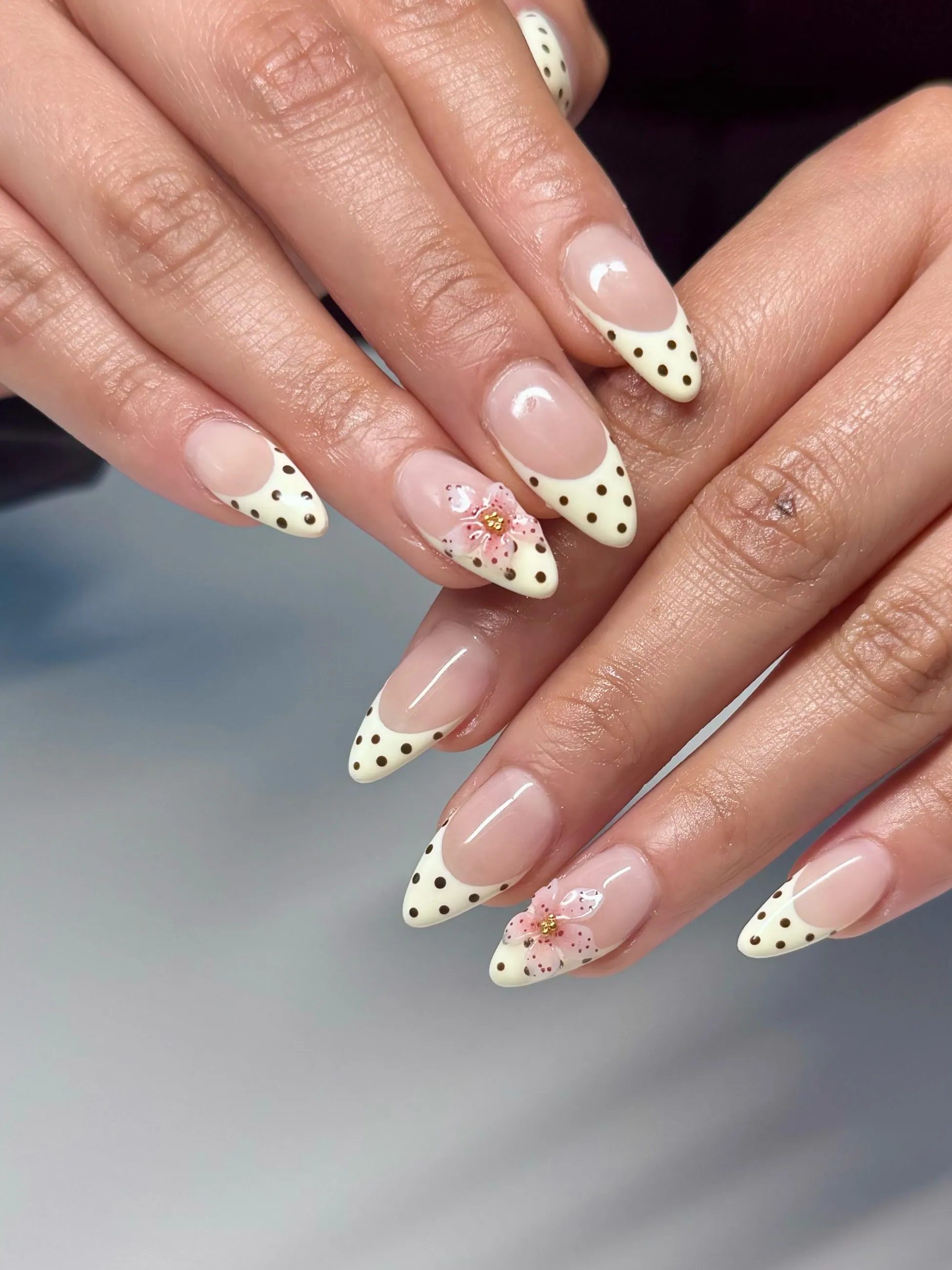 Pale yellow French tips with brown dots and pink flower accents