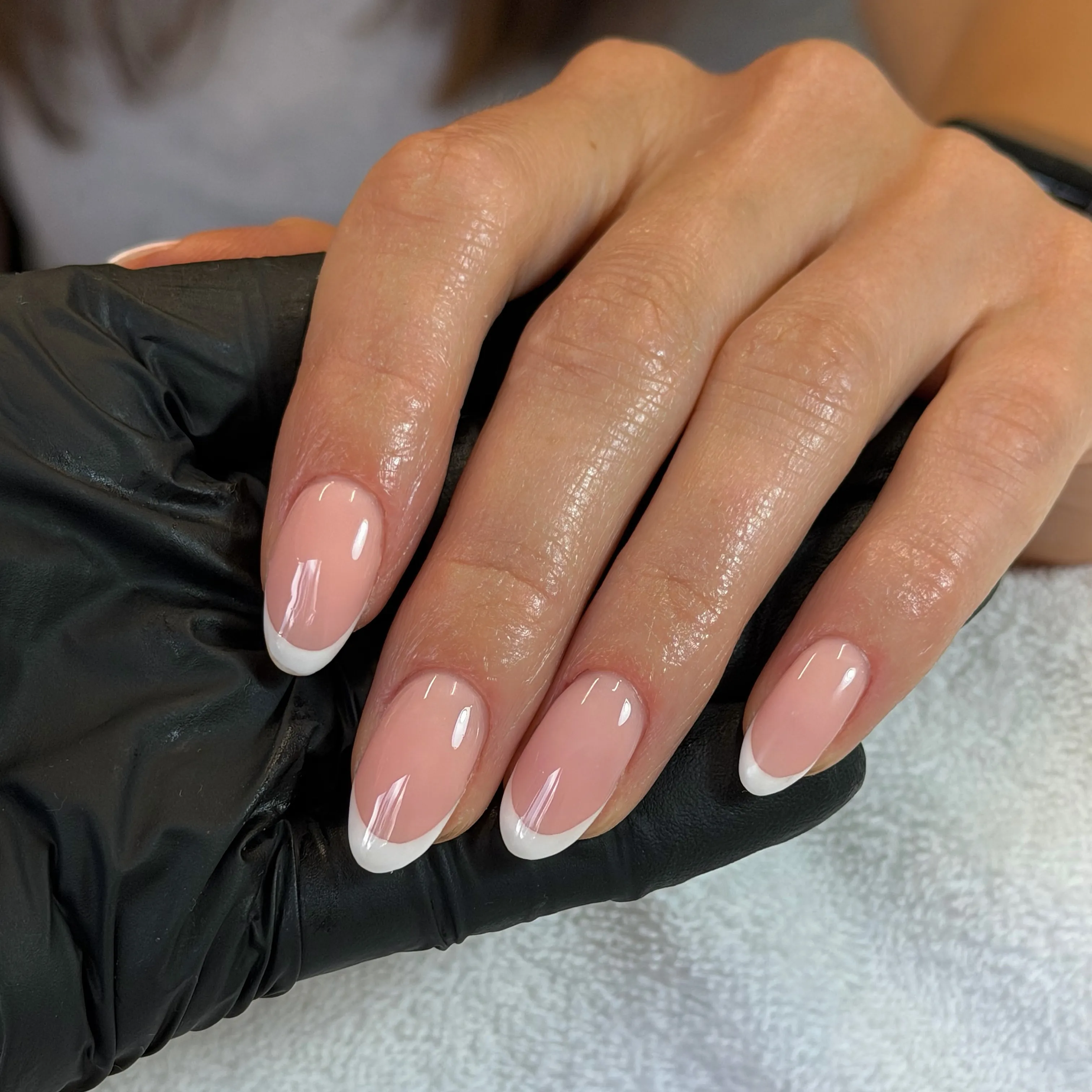 Glossy pink almond nails with slim white French tips