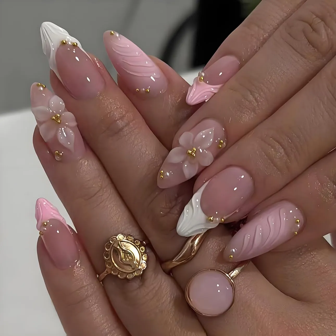 Pink and white French nails with raised petals ridges and gold beads