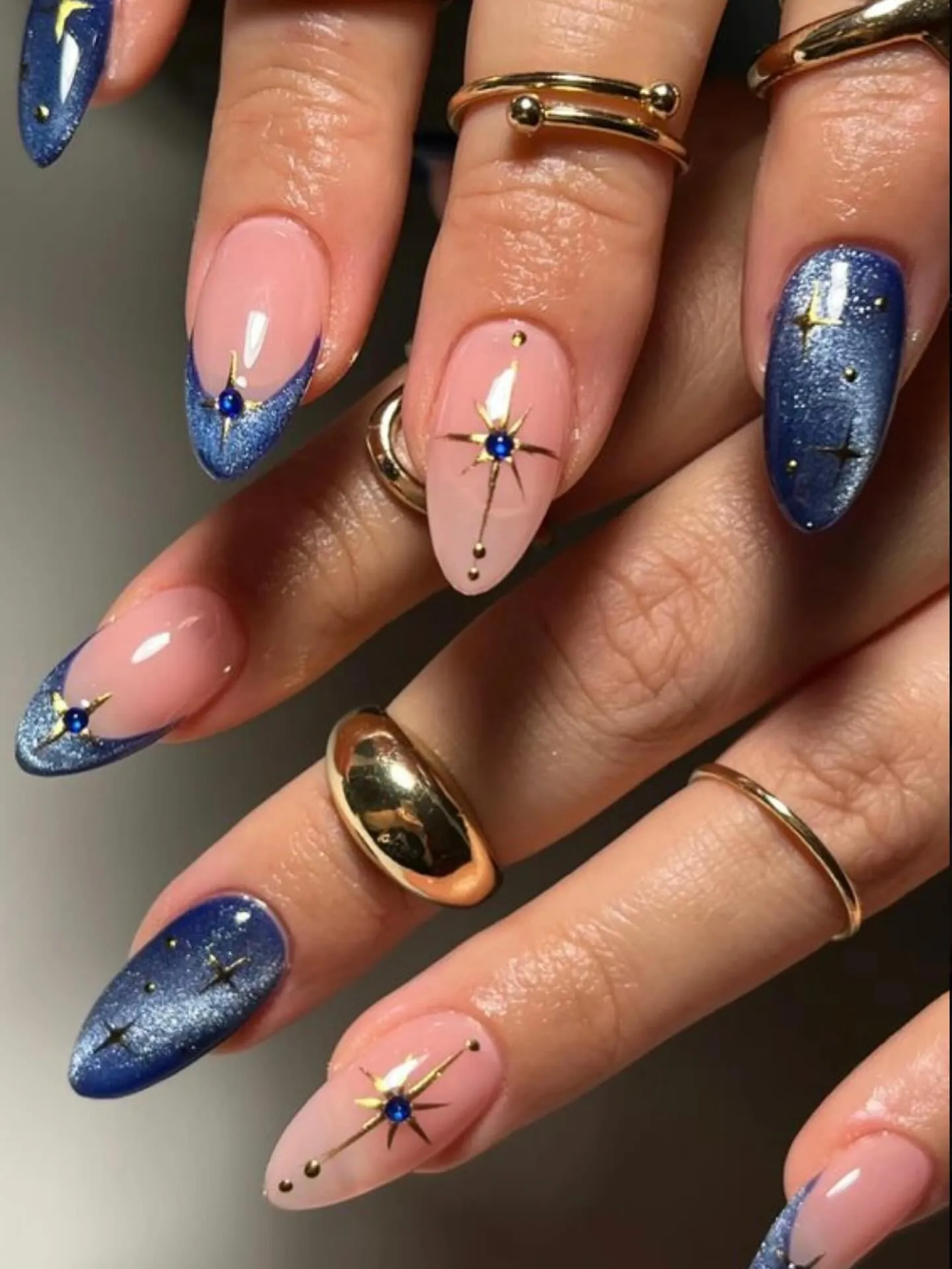 Shimmering blue French and solid nails with pink gold starburst accents
