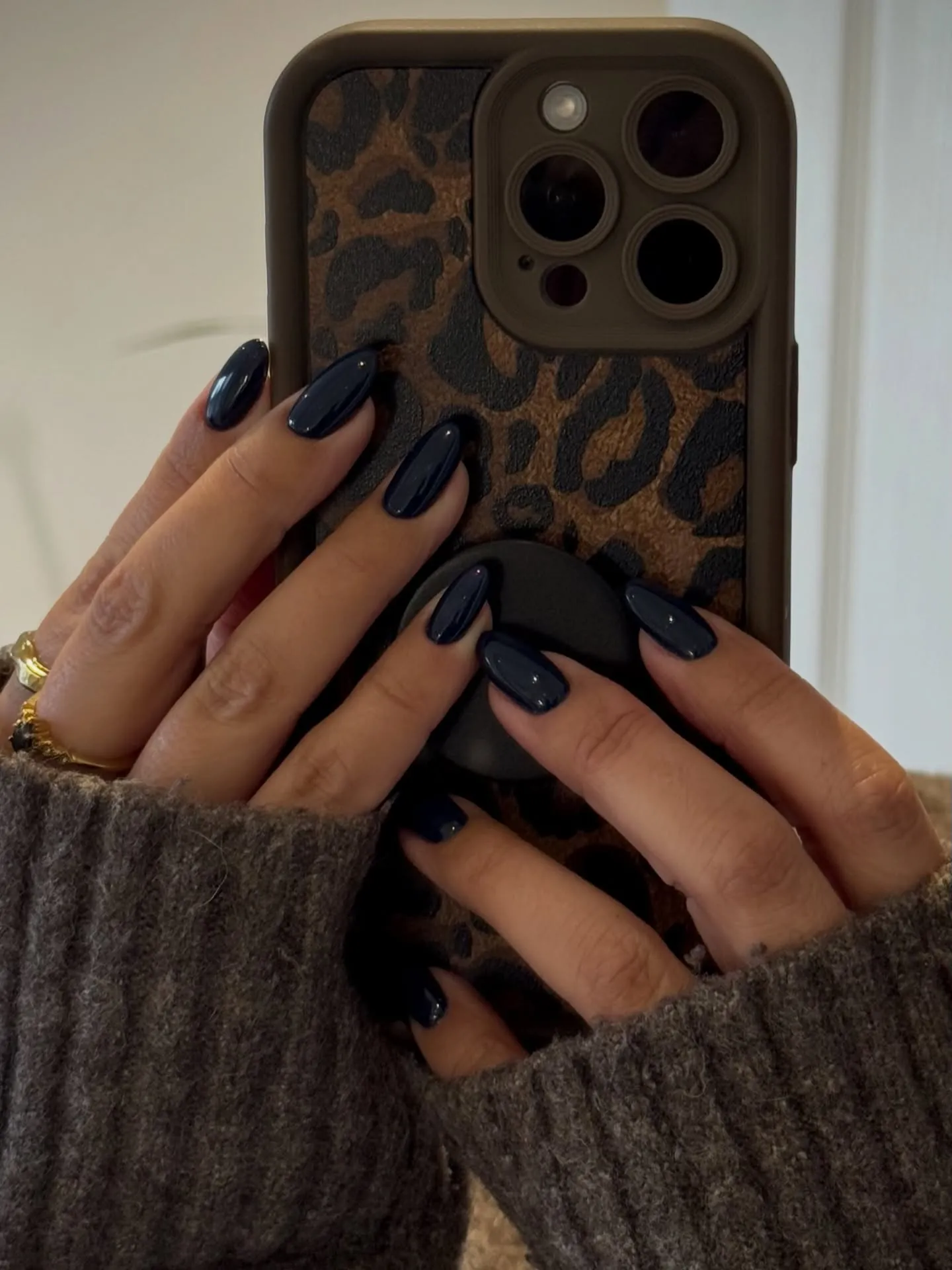 Glossy dark navy almond nails shown against a phone