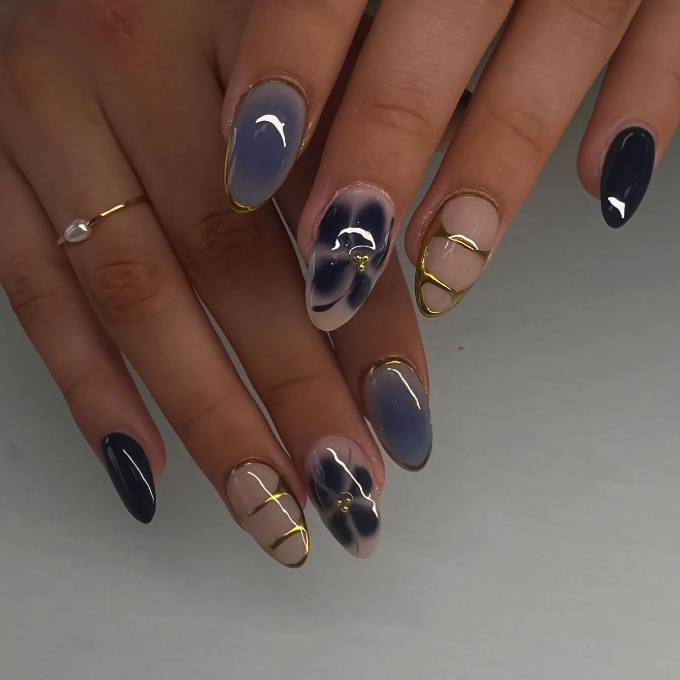Almond nails with smoky blue accents, navy flowers and gold bands on nude bases