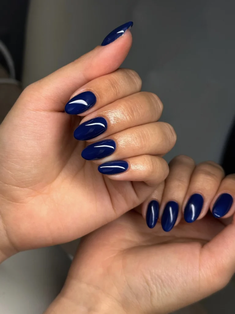 Glossy navy blue almond nails with a subtle reflective sheen
