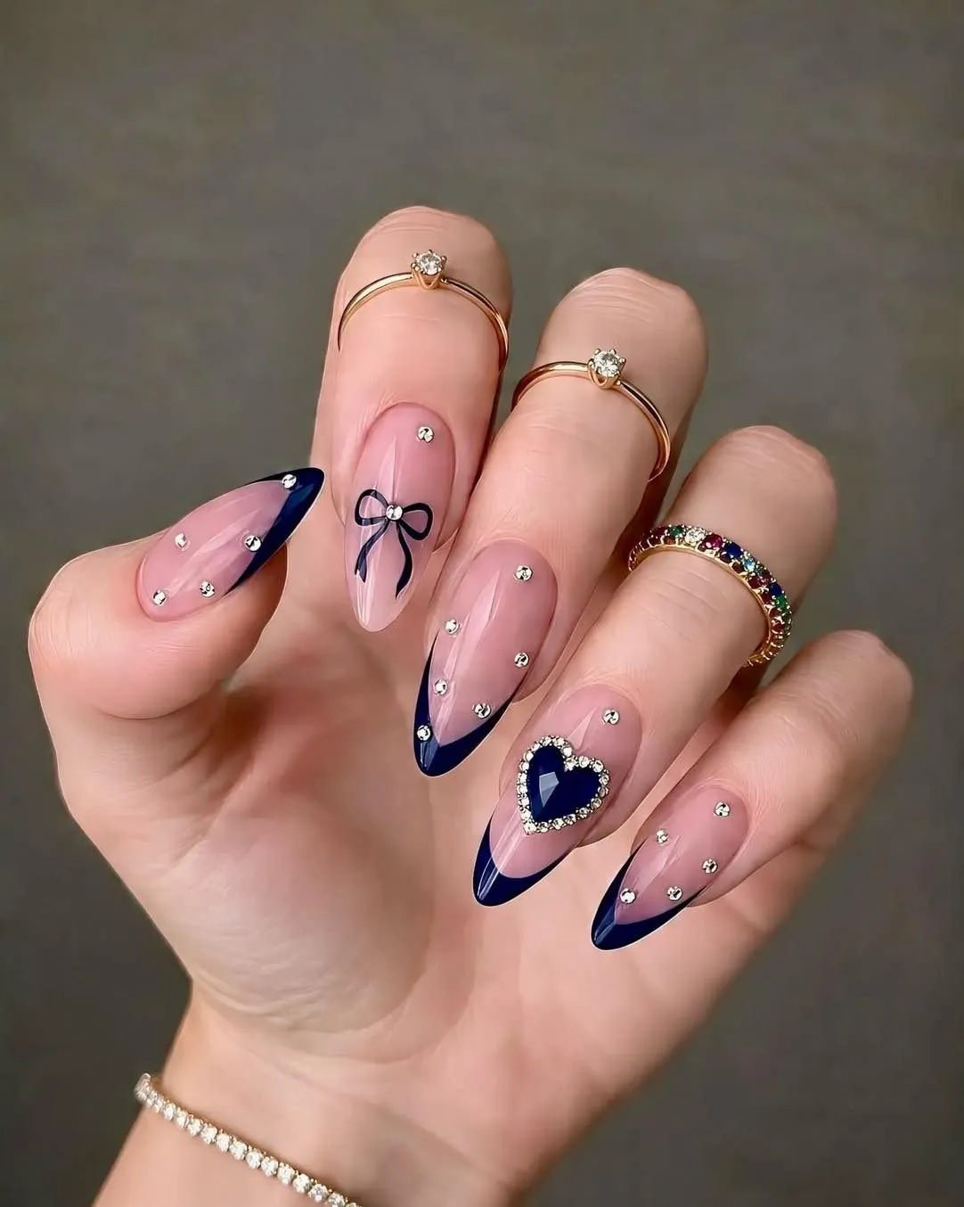 Pink almond nails with navy tips, a bow, small gems and a bordered heart