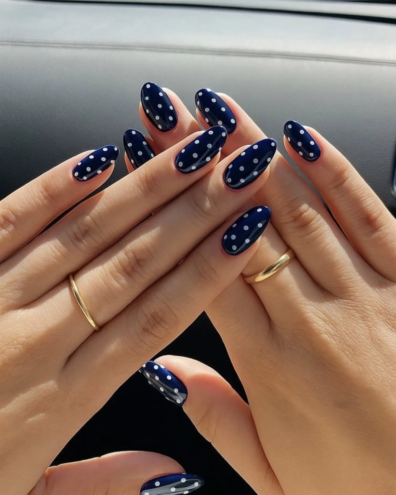 Navy almond nails with pale polka dots and a small sparkling accent