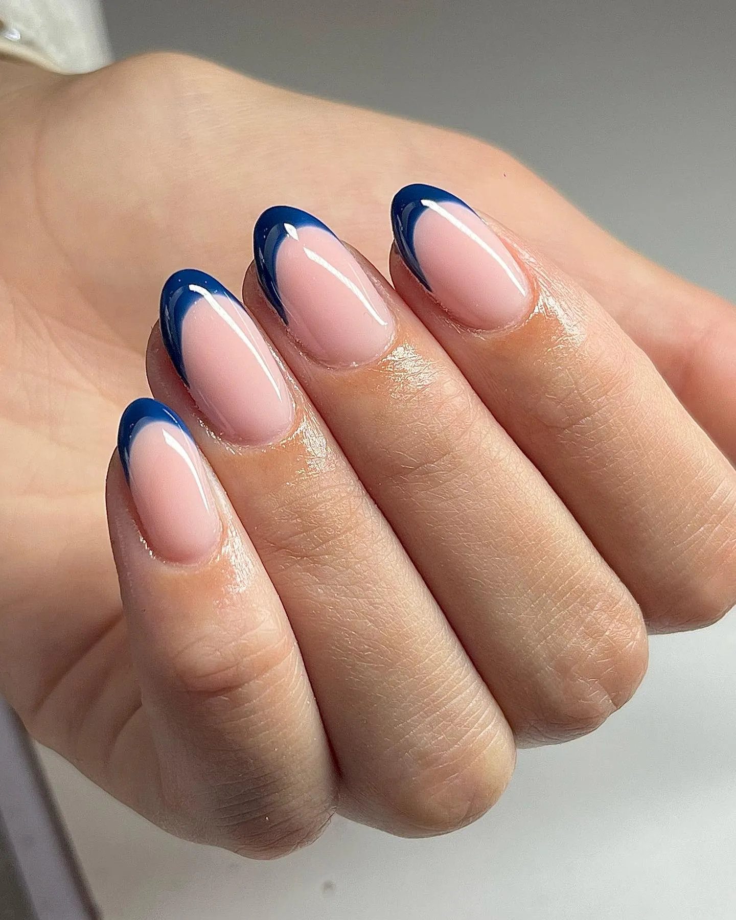 Pink almond nails with curved navy blue French tips
