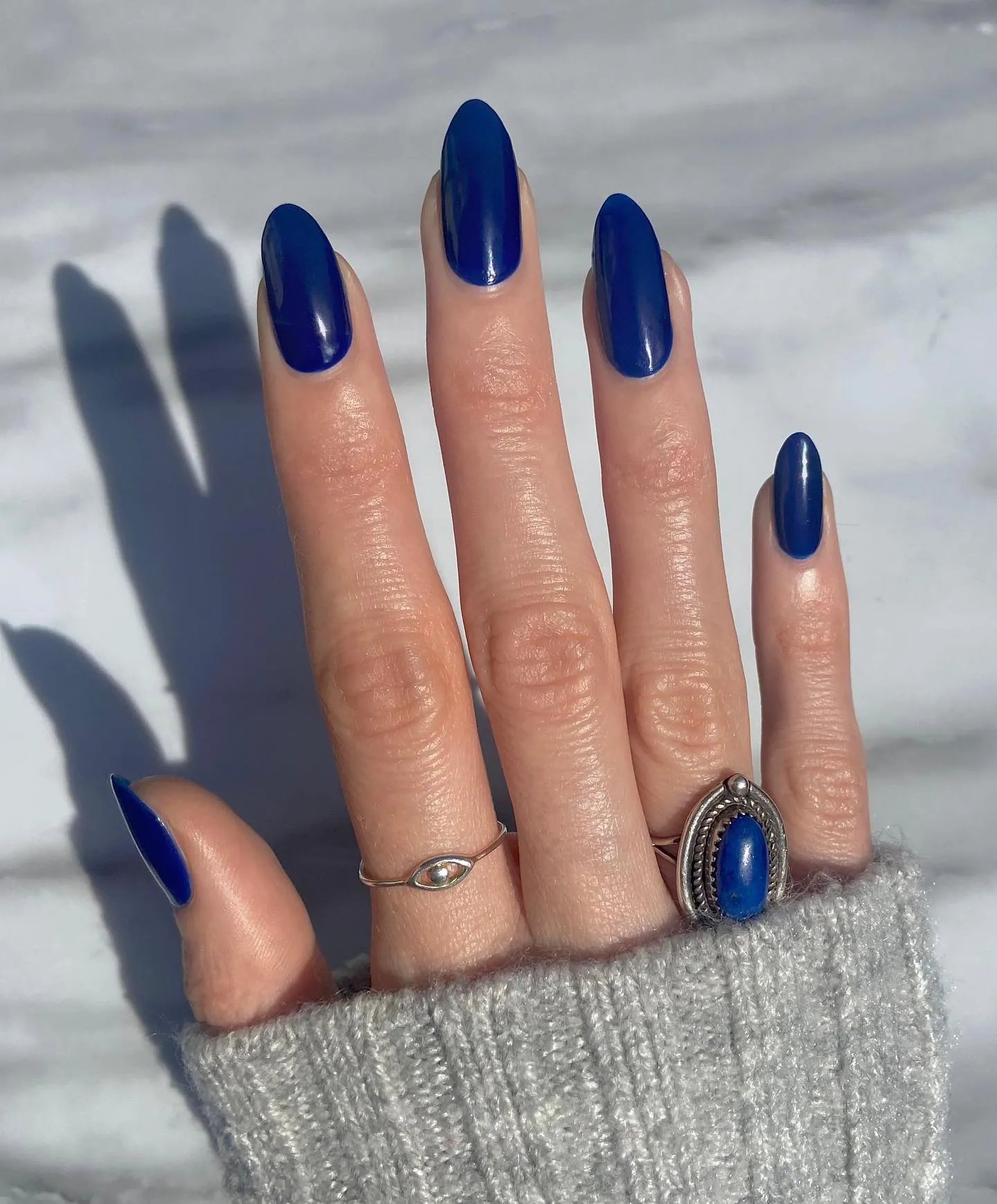 Long almond nails covered in glossy deep blue