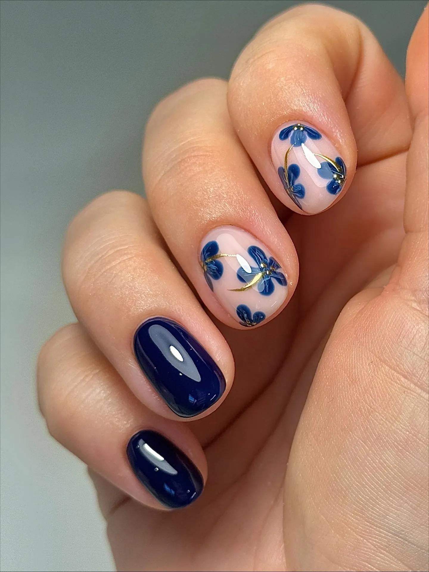 Navy nails with blue floral designs on light accent nails