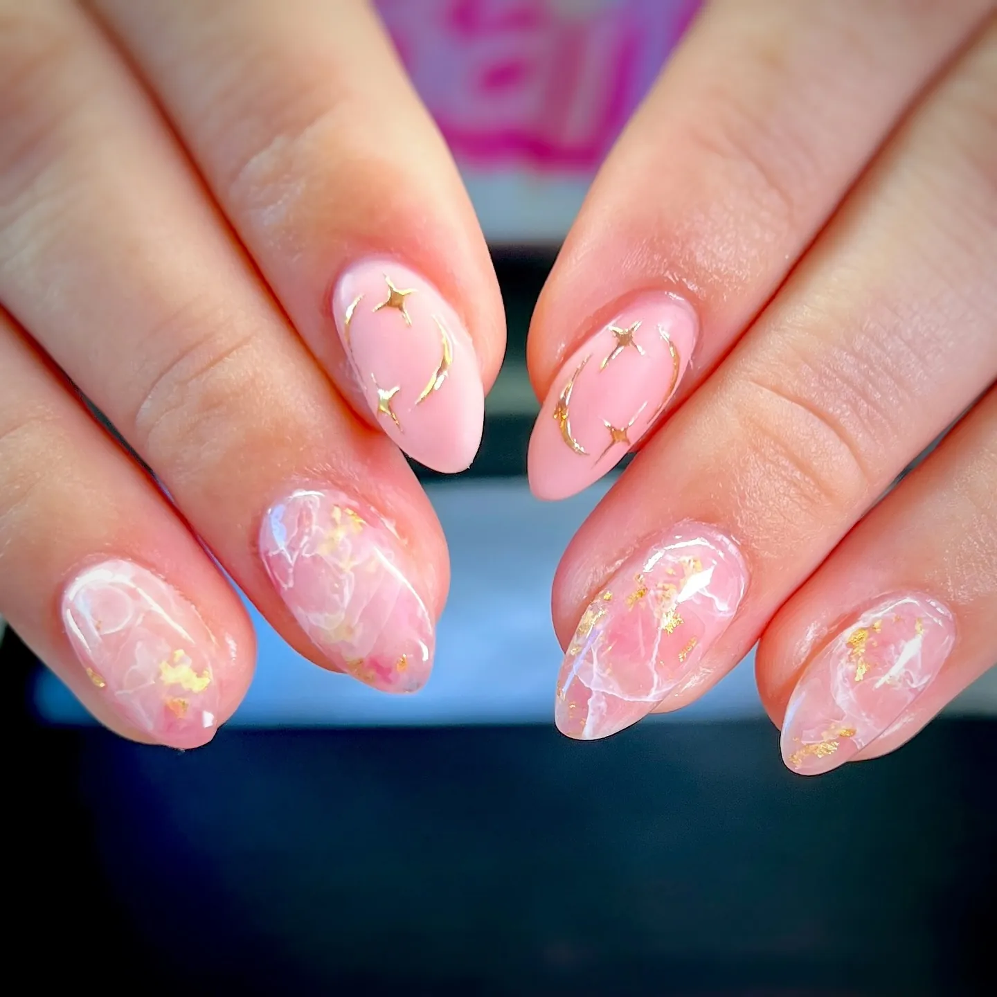 Short pink nails with pale marble lines and scattered gold flecks