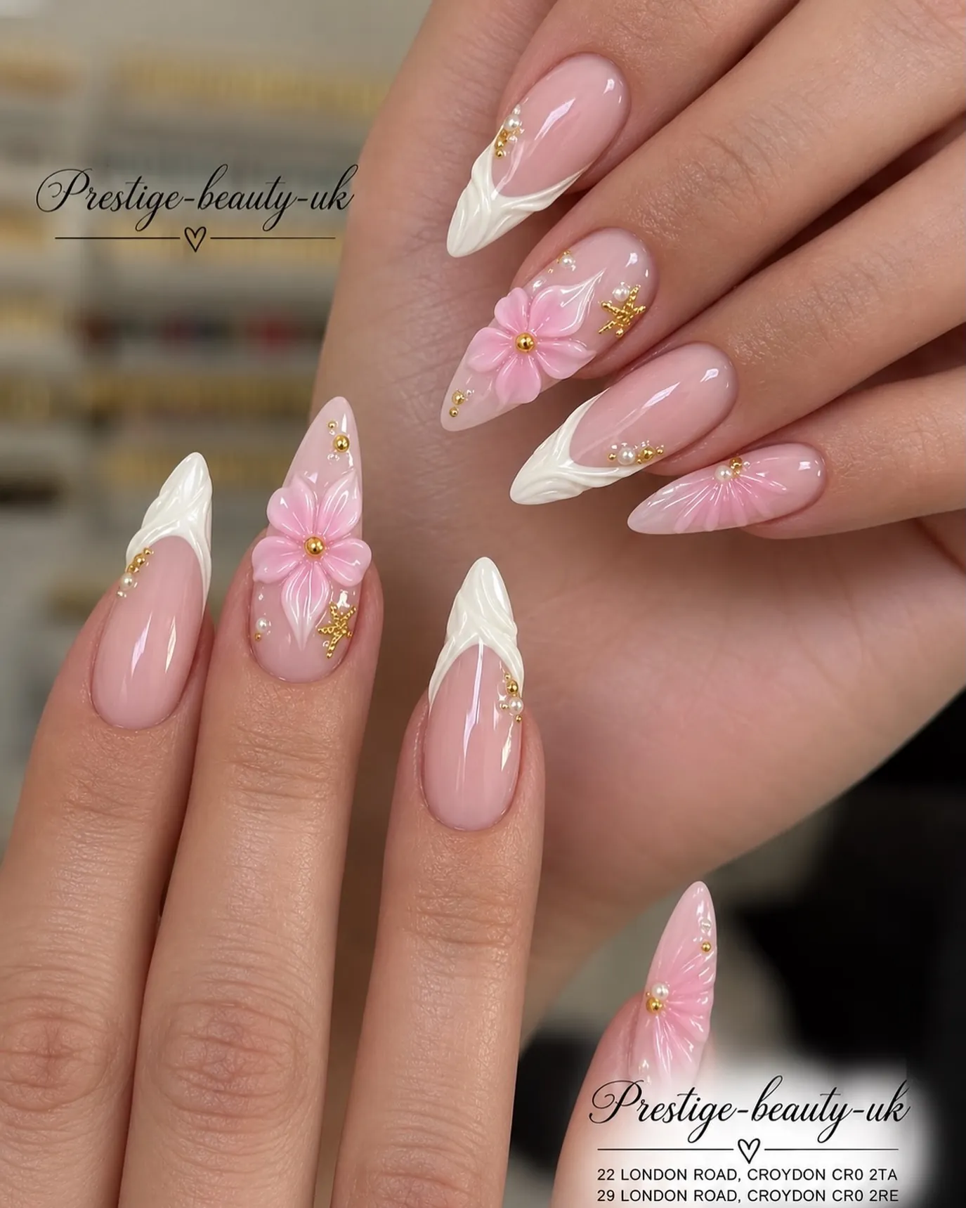 Long pointed pink nails with textured white tips, raised pink flowers and gold accents