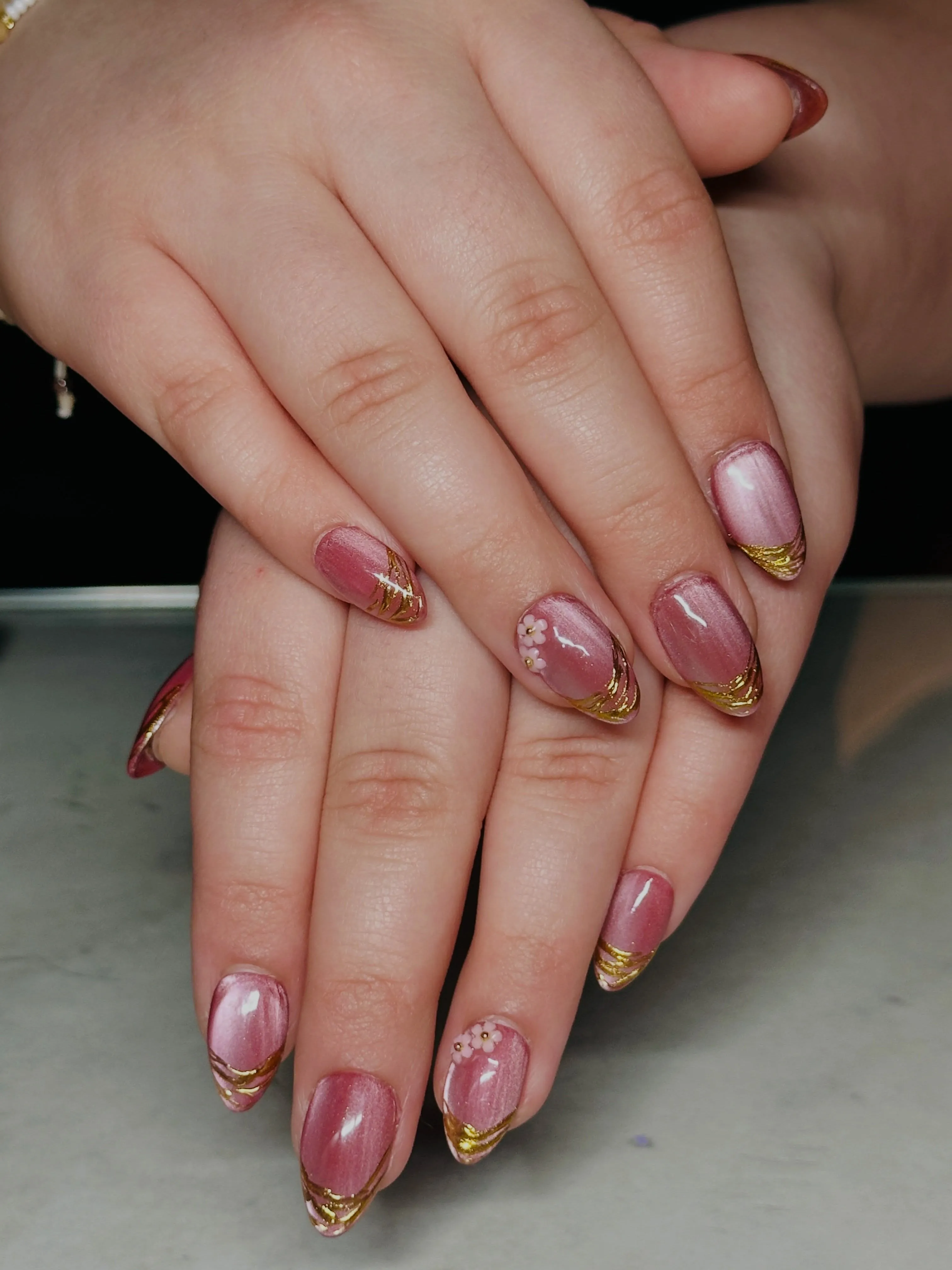 Short pink nails with marbled accents and irregular gold French edges