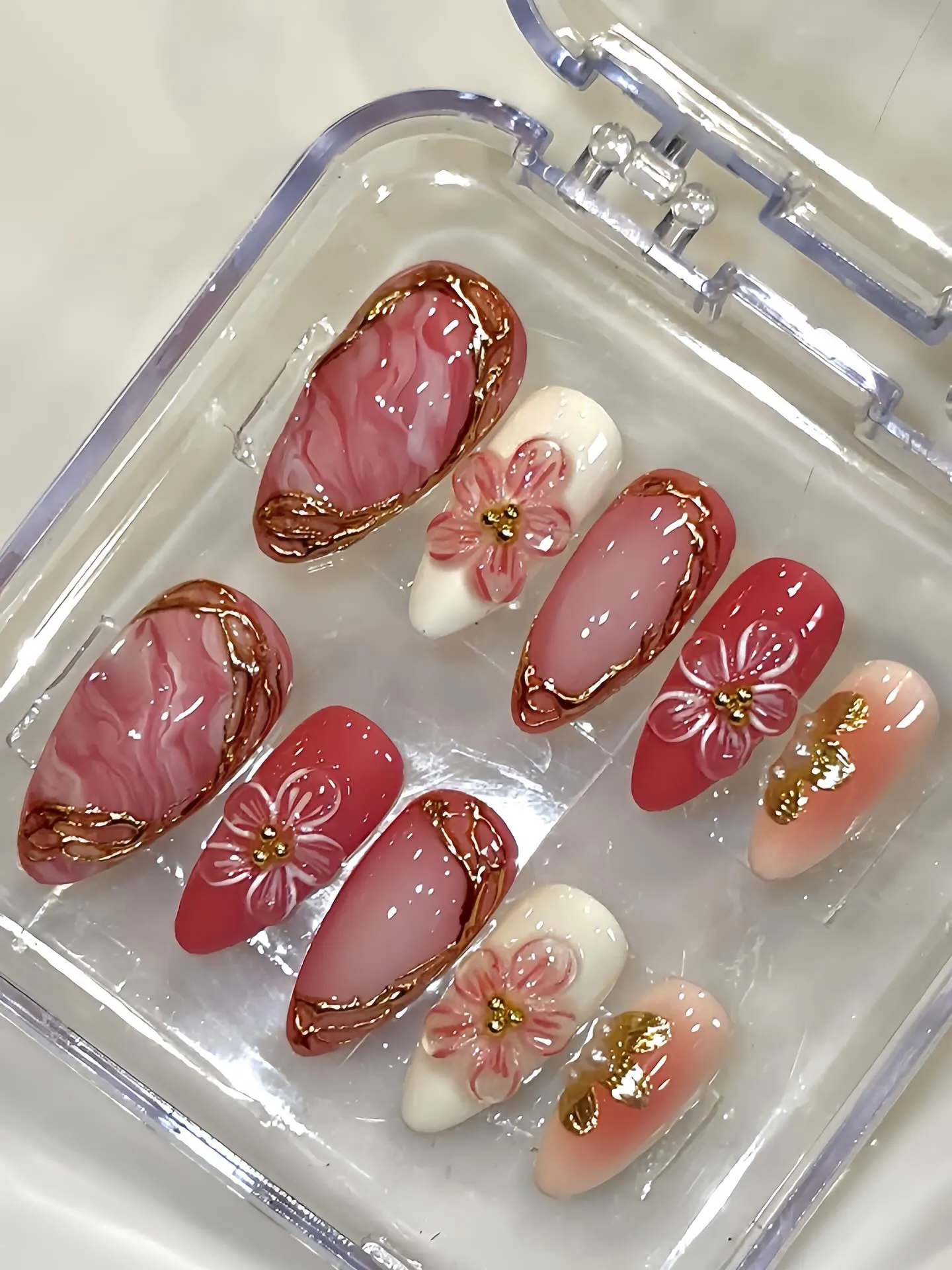 Displayed pink and cream nails with marbling, raised flowers and gold frames