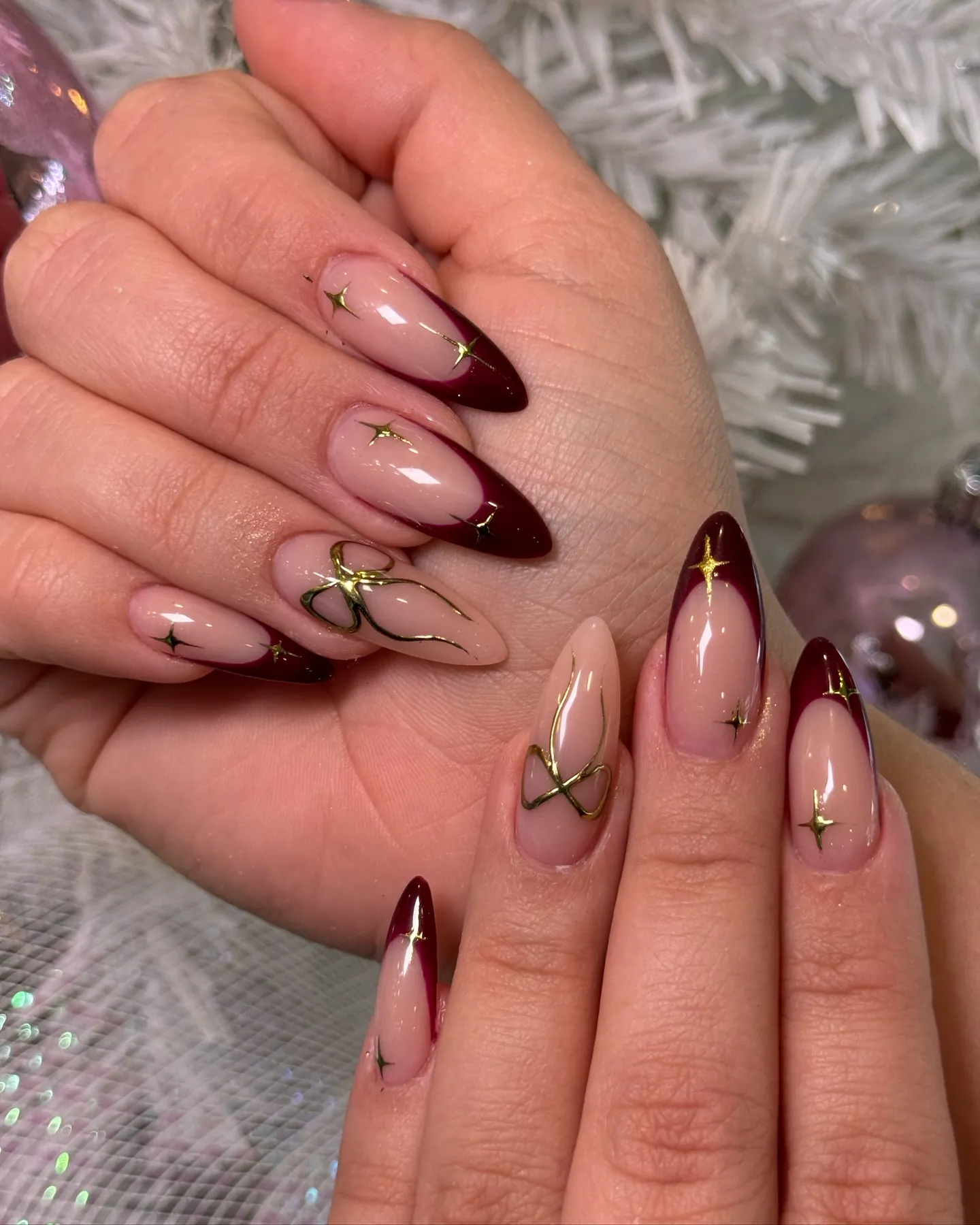 Deep red almond French nails with gold stars and gold bow accents