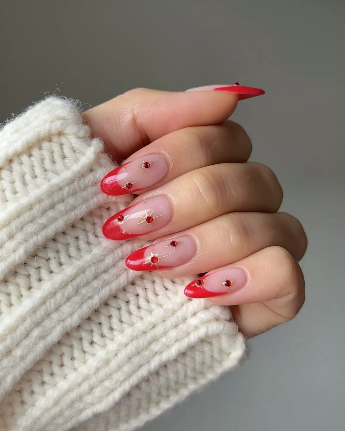 Long pink almond nails with red French tips and small red and metallic details