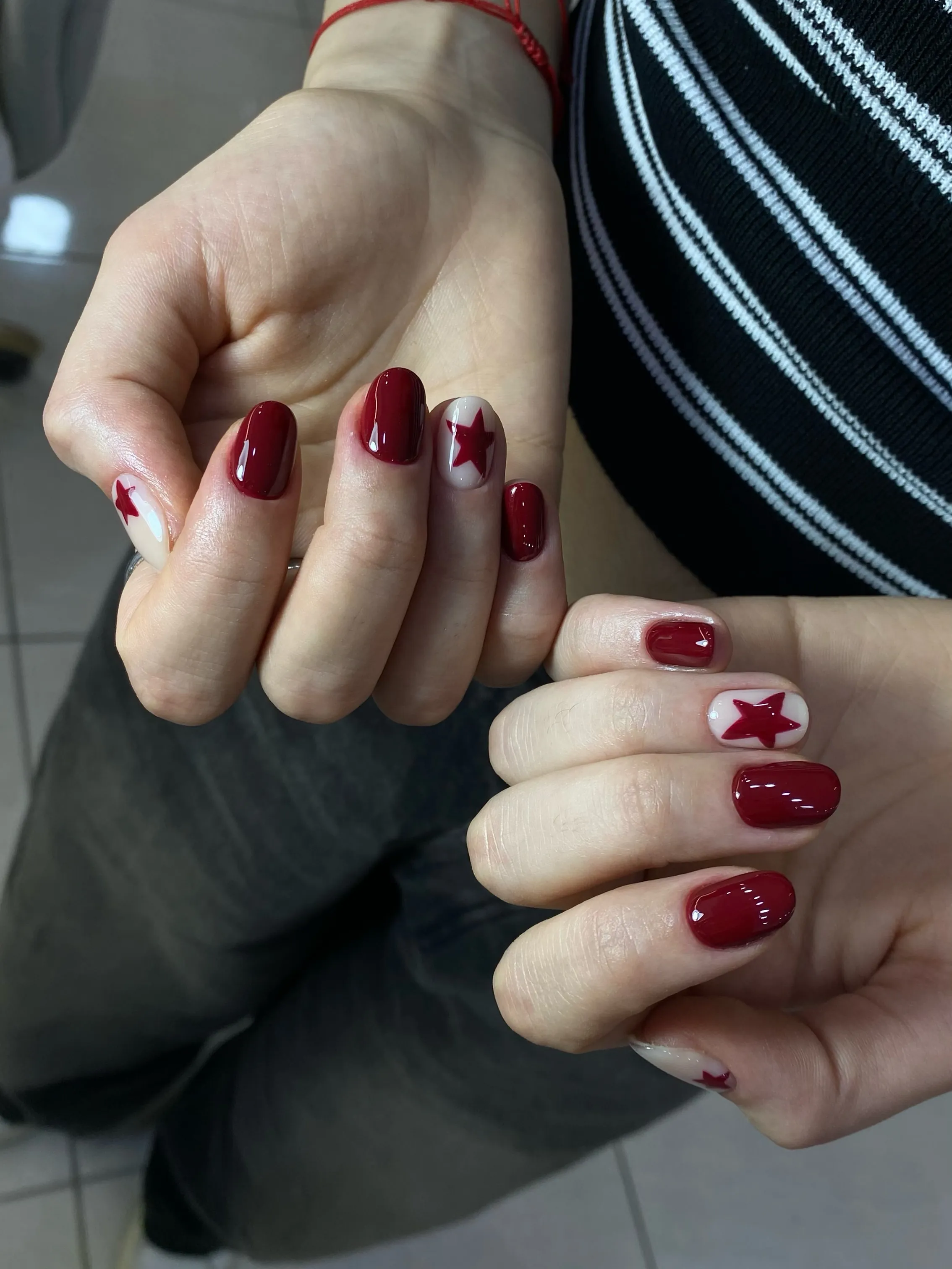 Short solid burgundy nails with red stars on pale accent nails