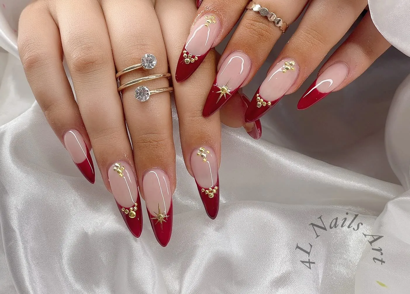 Long red French nails with pink bases and fine gold scroll details